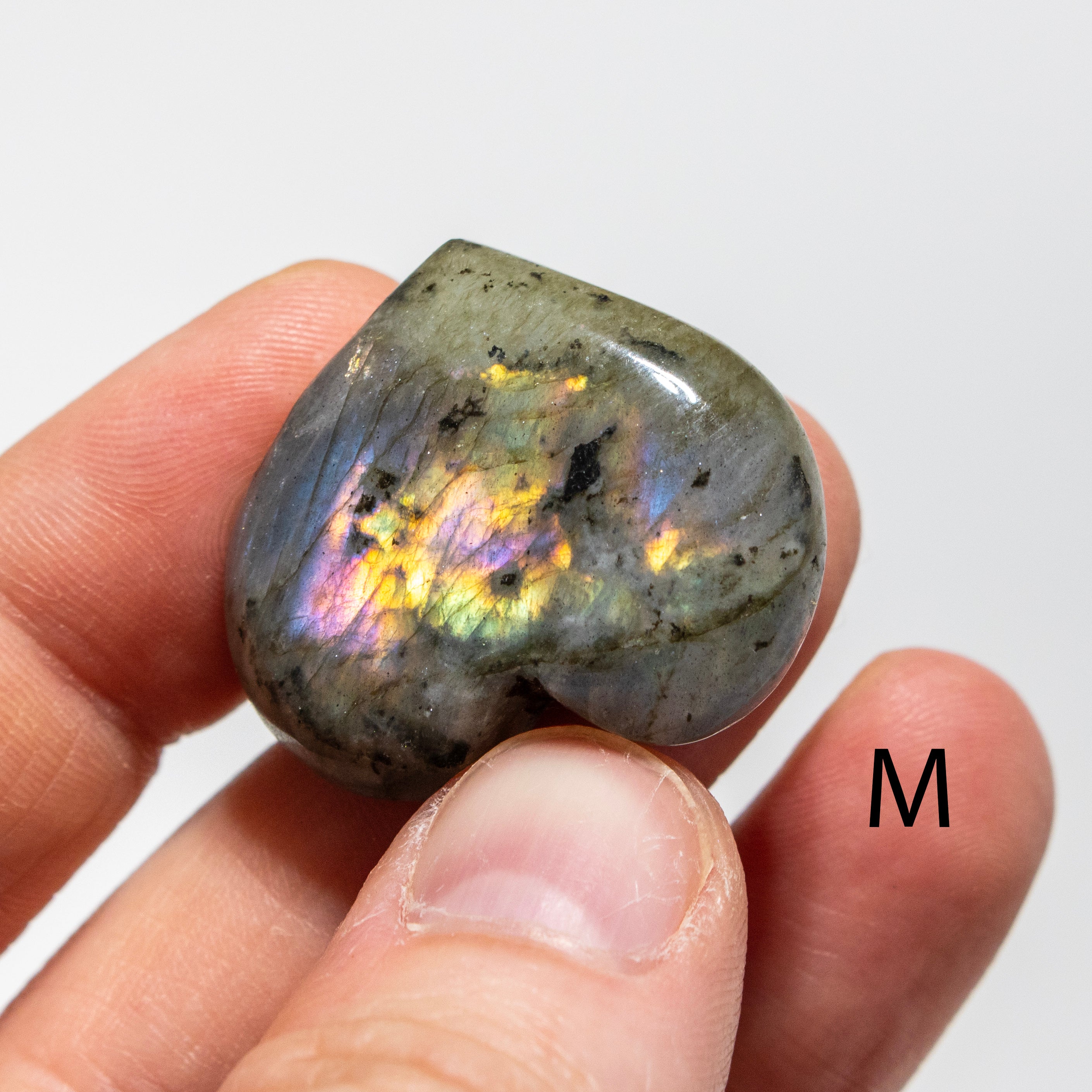 Labradorite stone held between fingers with a plain background