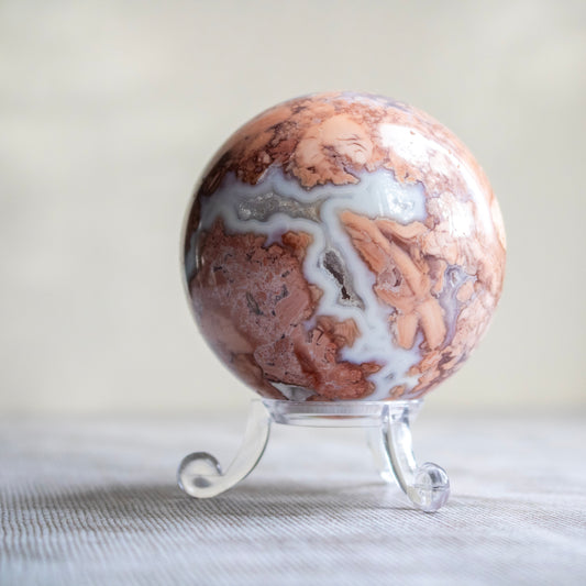 Marble-patterned sphere on a stand with a neutral background