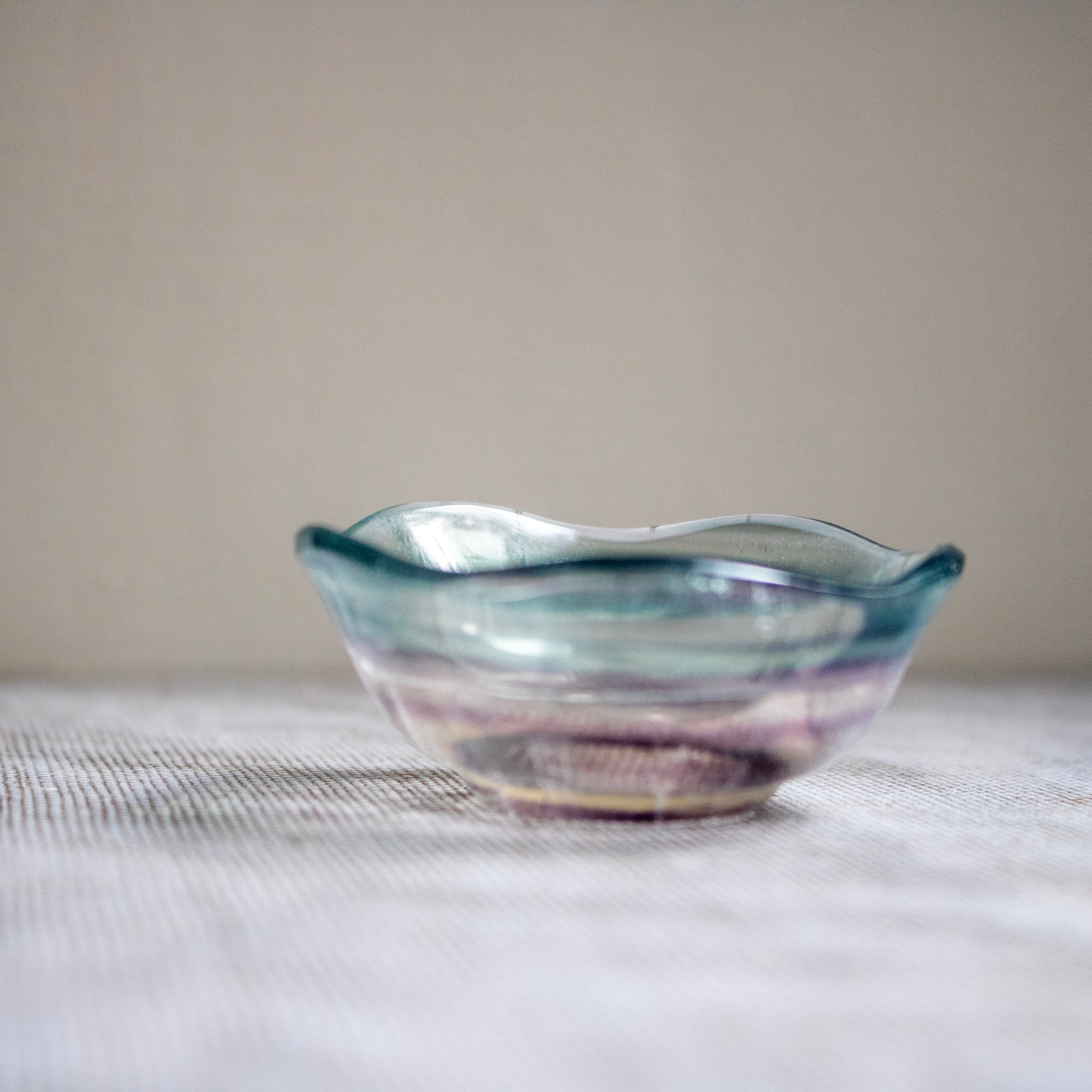Crystal bowl with blue and purple hues on a textured surface