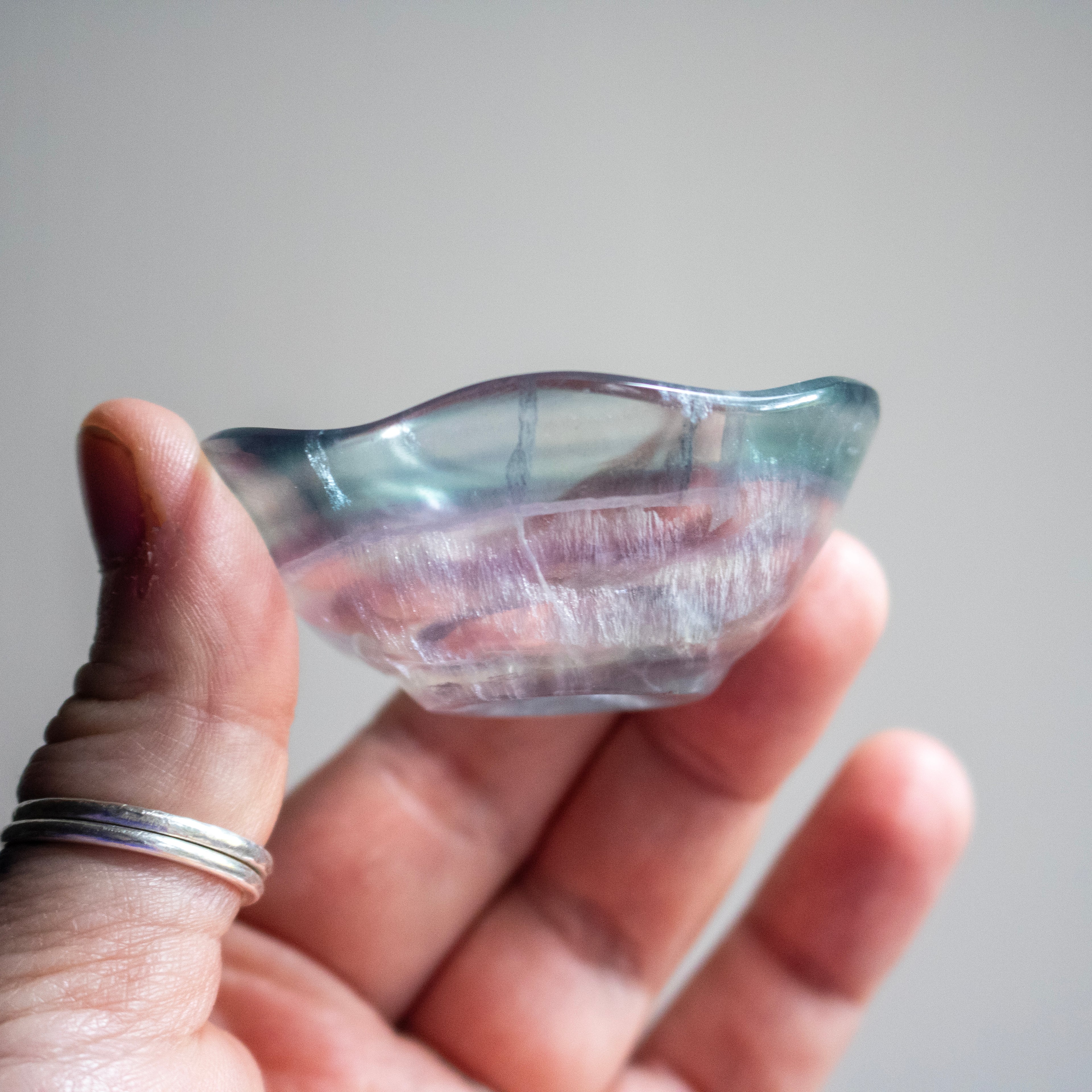 Hand holding a clear crystal with a gray background