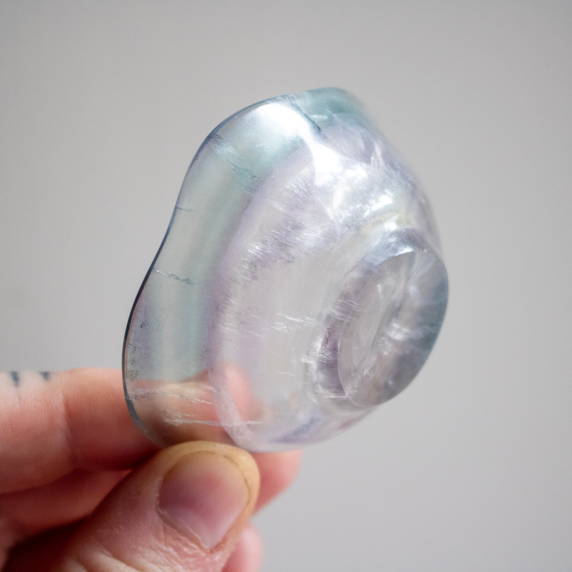 Clear stone held in a hand against a neutral background
