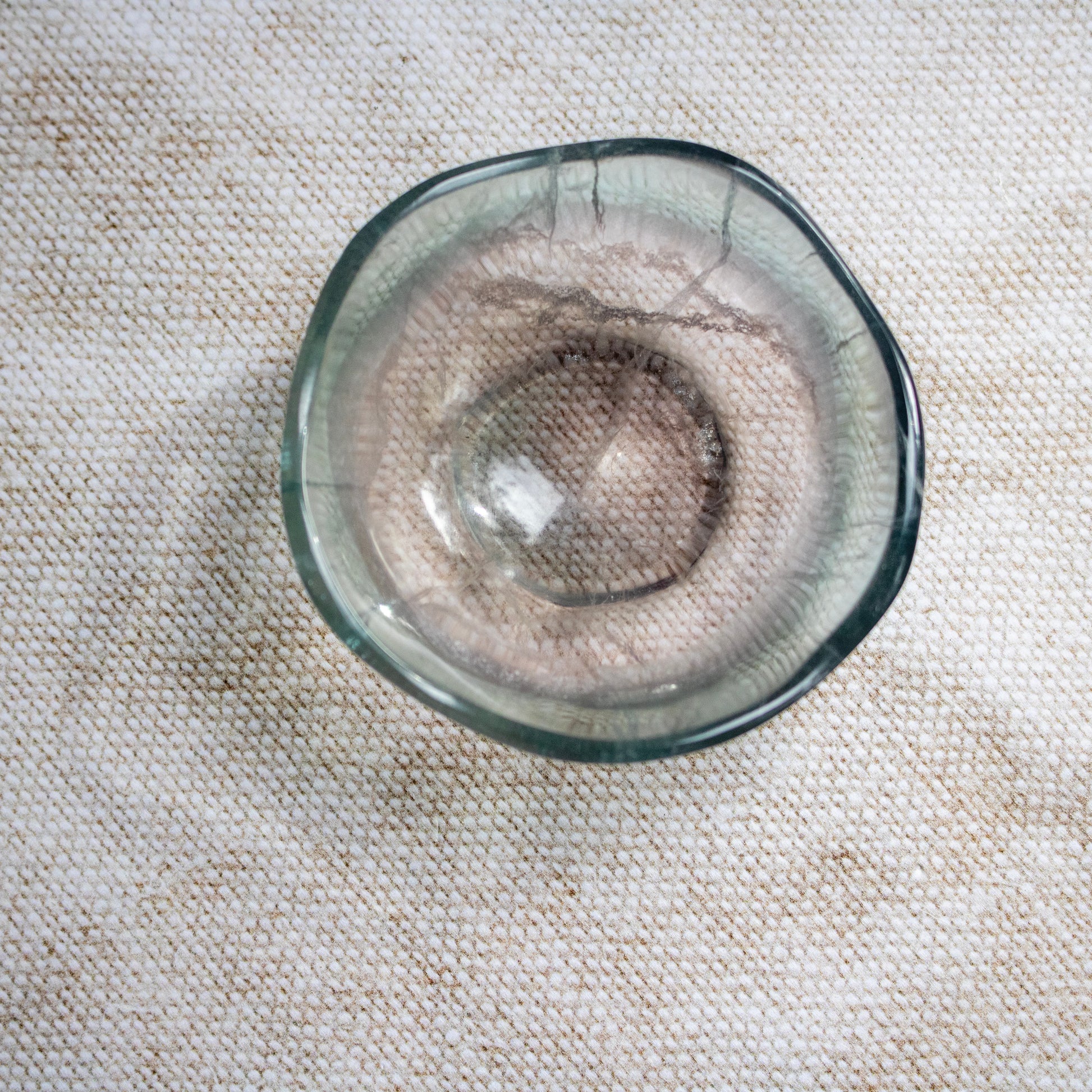 Clear crystal bowl on a textured beige surface