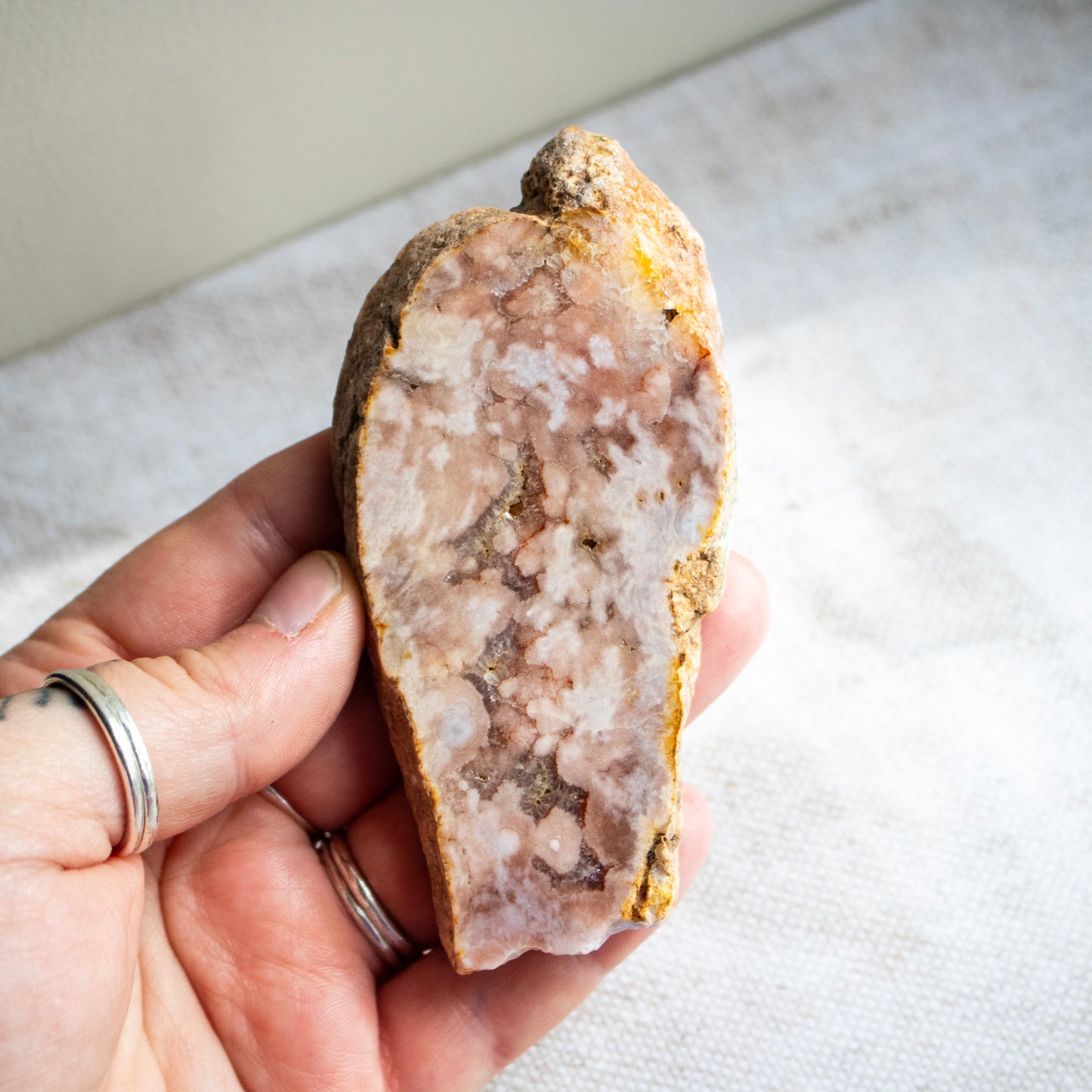 Hand holding a large crystal or mineral stone on a light background
