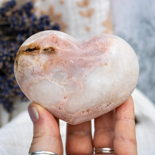 Heart-shaped stone held in a hand with a blurred background