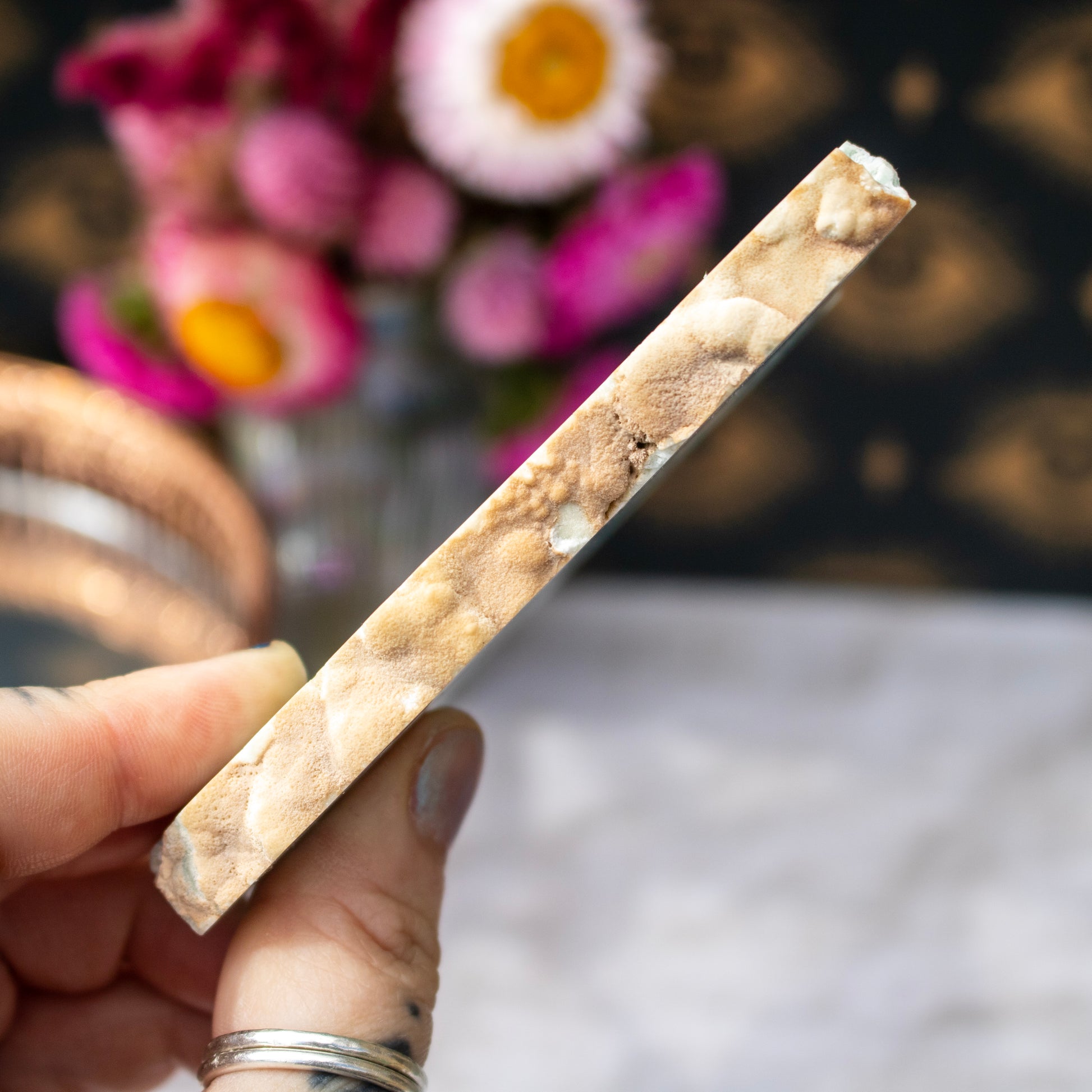 Hand holding a stone with a blurred floral background