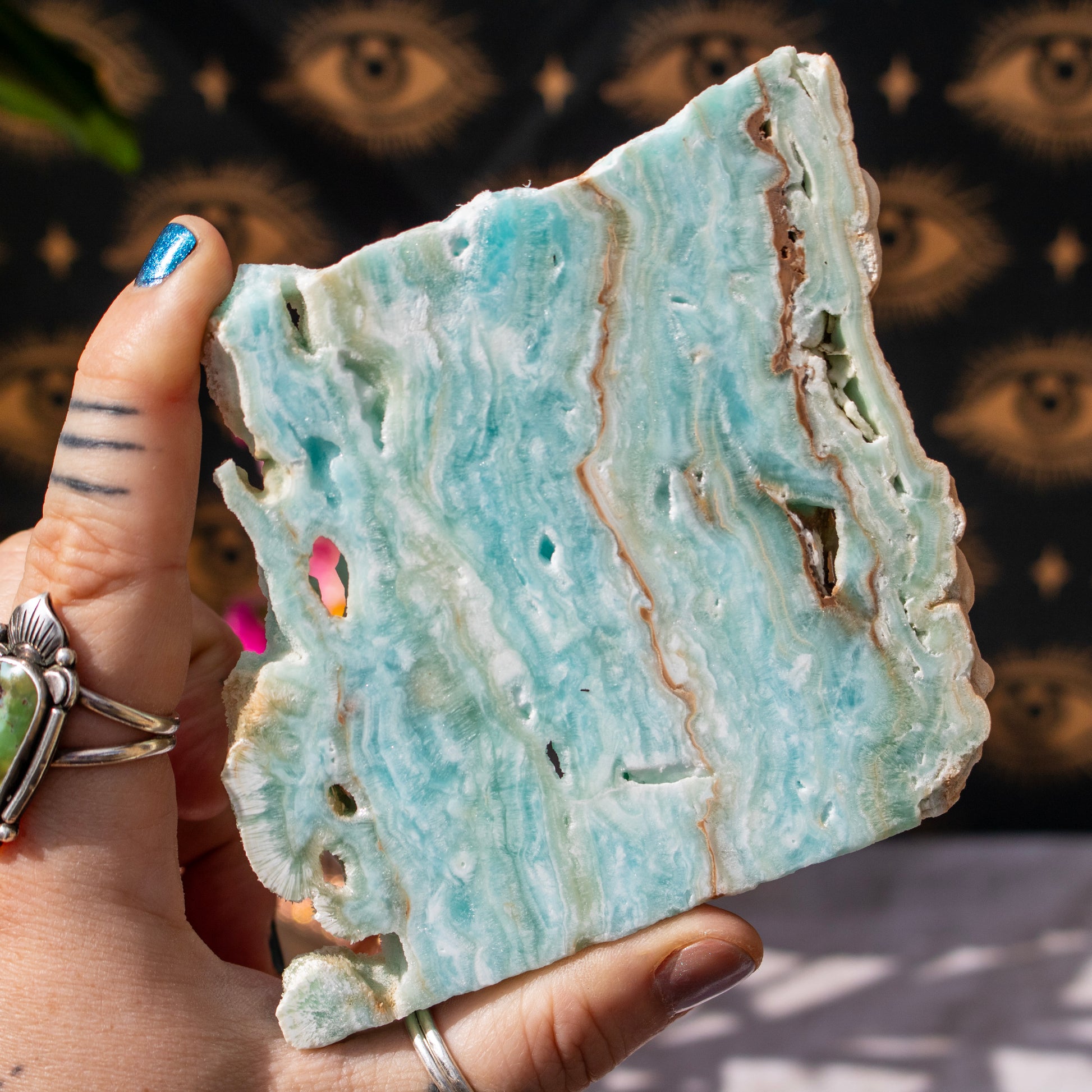 Hand holding a piece of light blue and white marbled stone with a blurred background