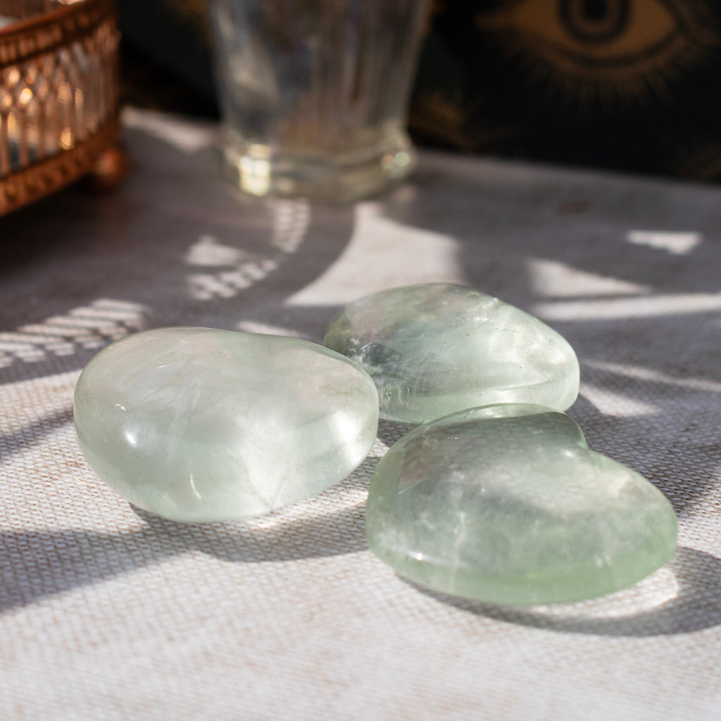 Three green crystals on a textured surface with a blurred background