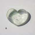 Heart-shaped green stone on a light gray background
