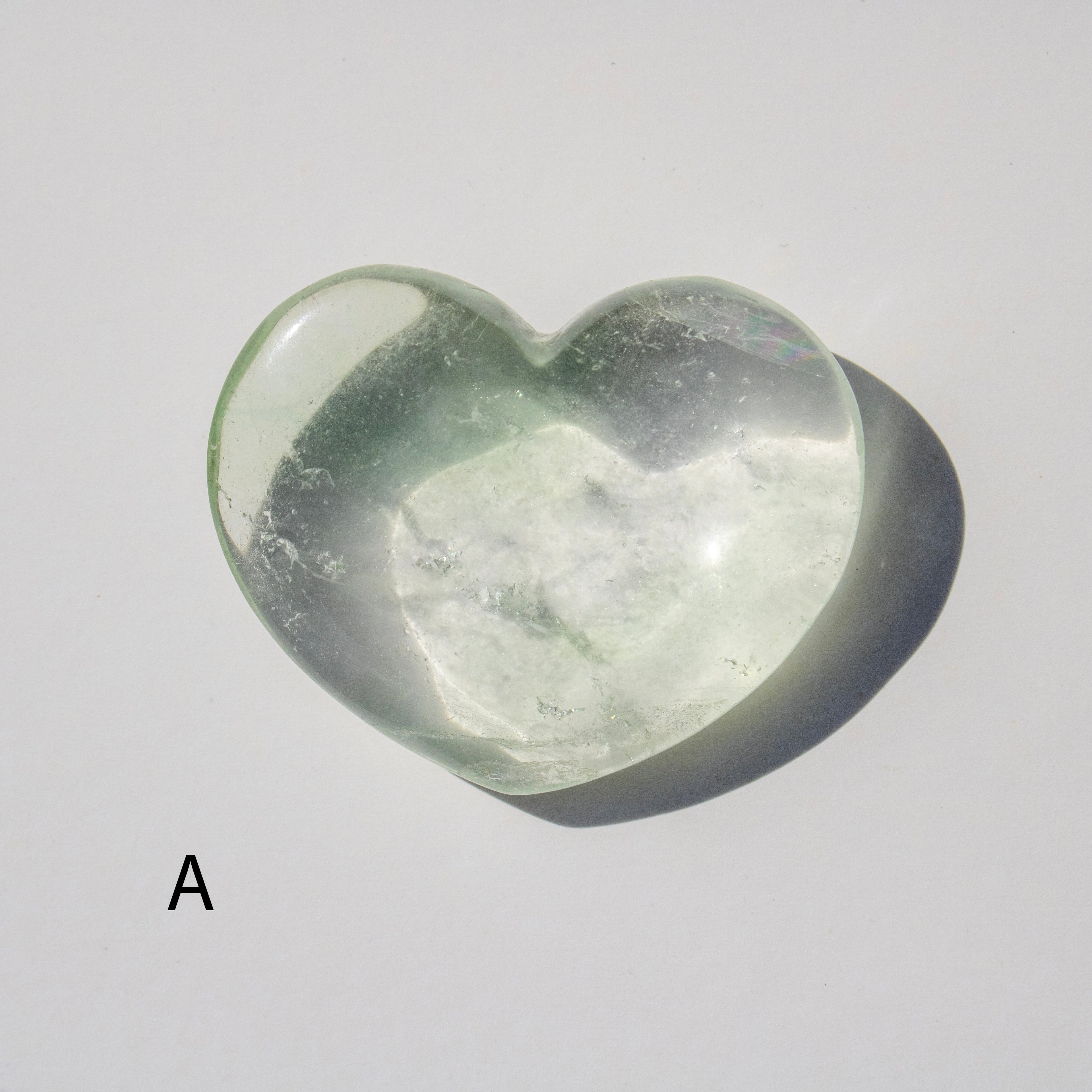 Heart-shaped green stone on a light gray background