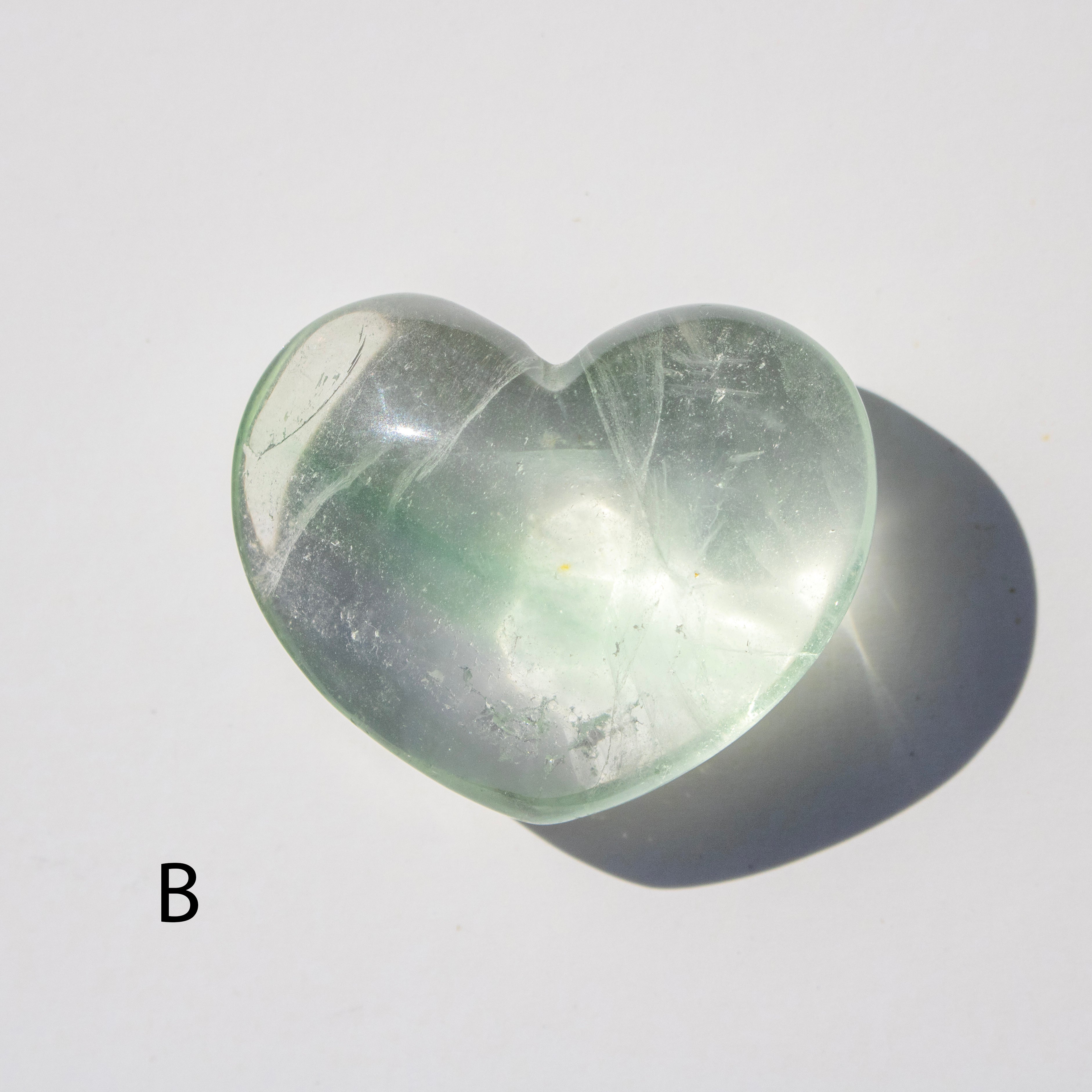 Heart-shaped green stone on a white background