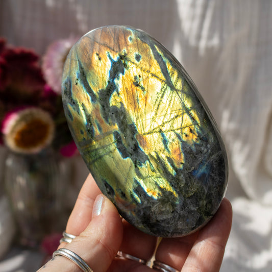 Hand holding a yellow crystal rock against a blurred background