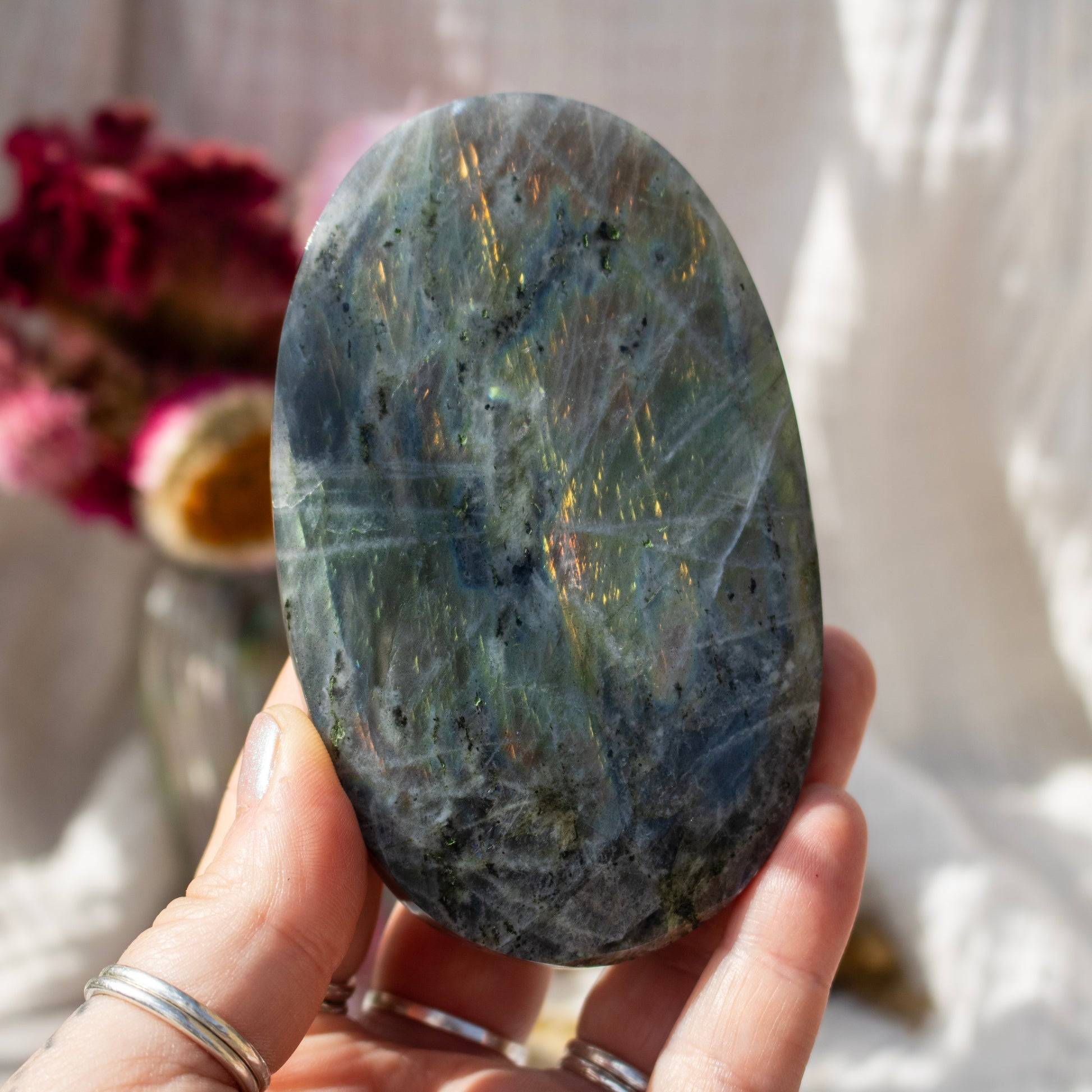 Hand holding a large labradorite stone with a blurred background