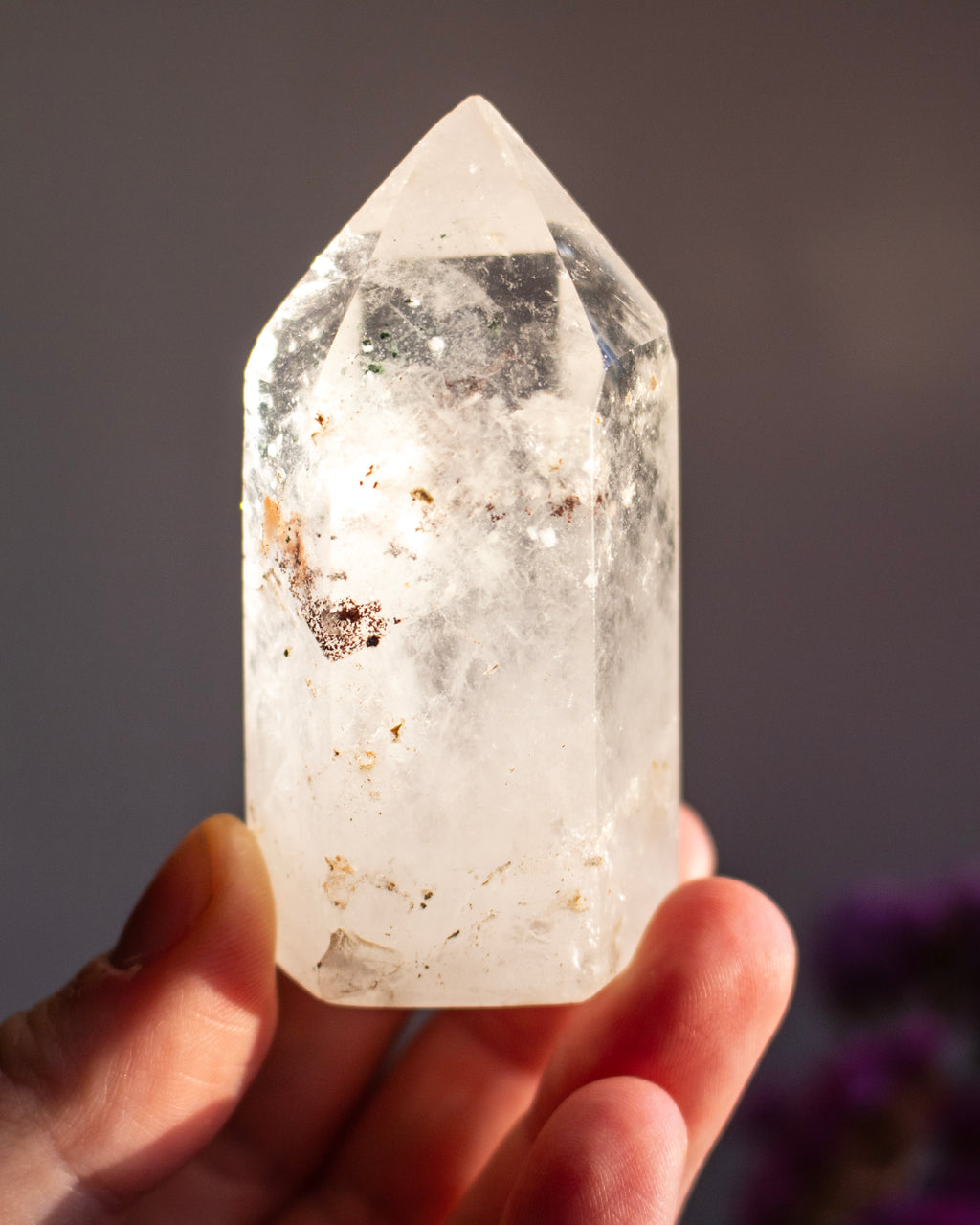 Clear crystal held in a hand against a blurred background