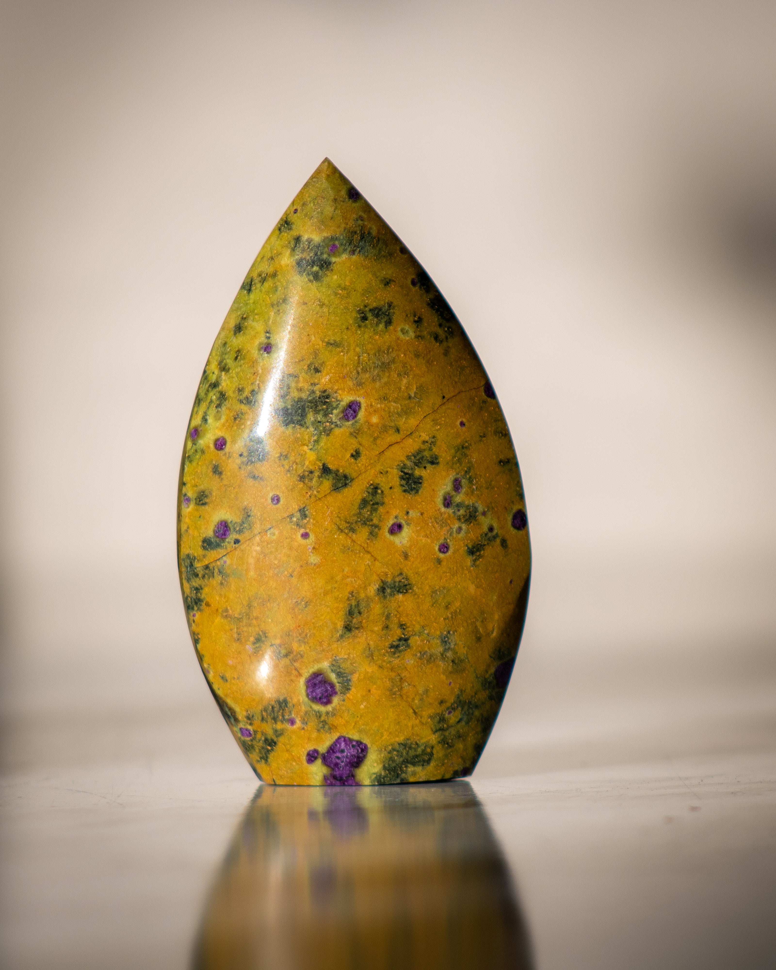 Decorative stone with yellow and green marbled pattern on a reflective surface