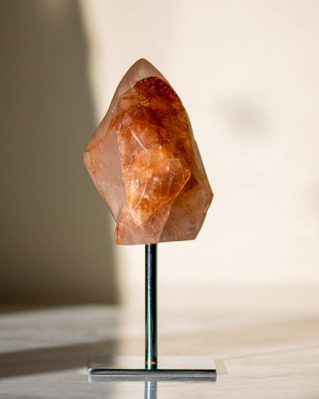 orangey red crystal shaped like a flame on a sliver metal stand