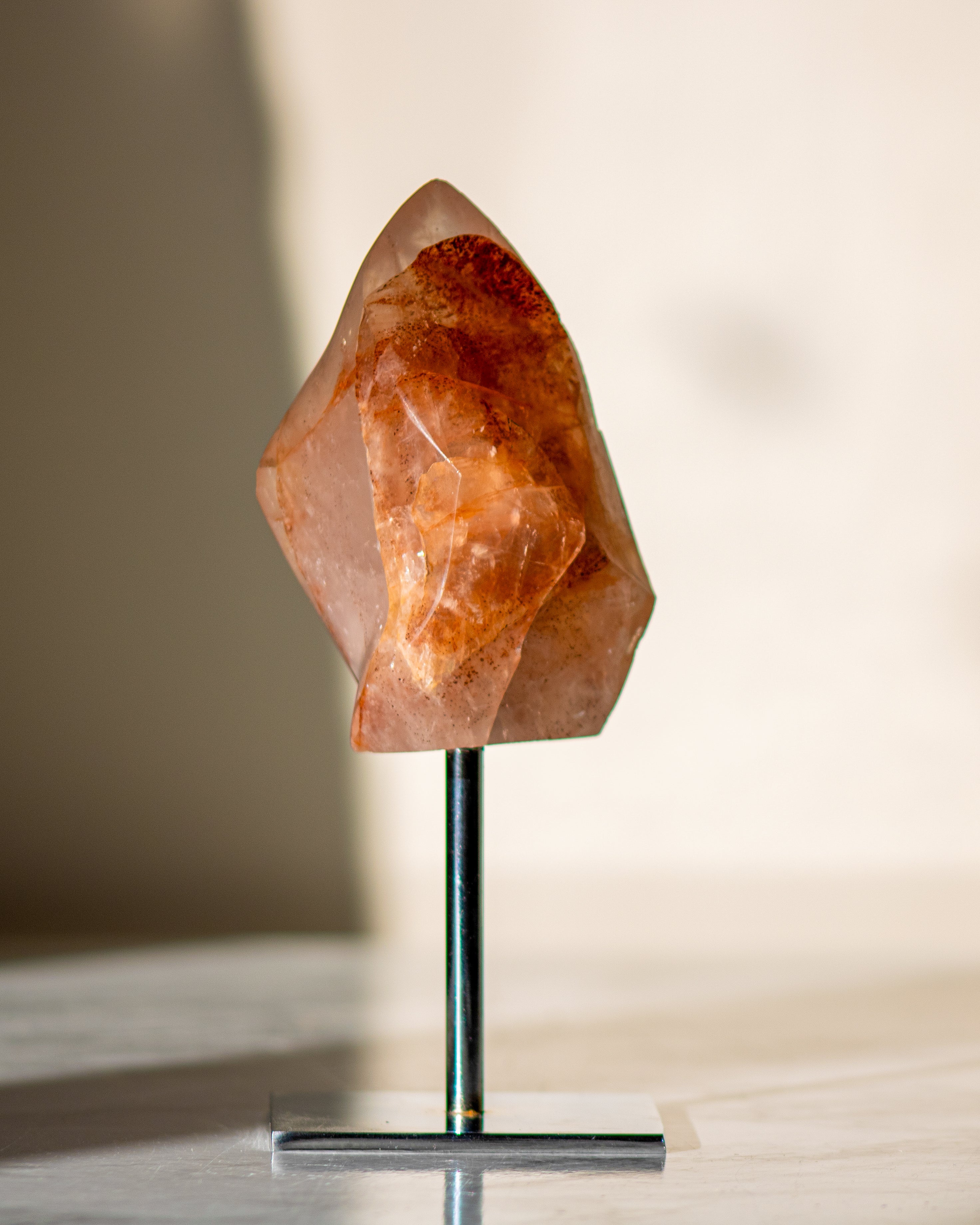 orangey red crystal shaped like a flame on a sliver metal stand