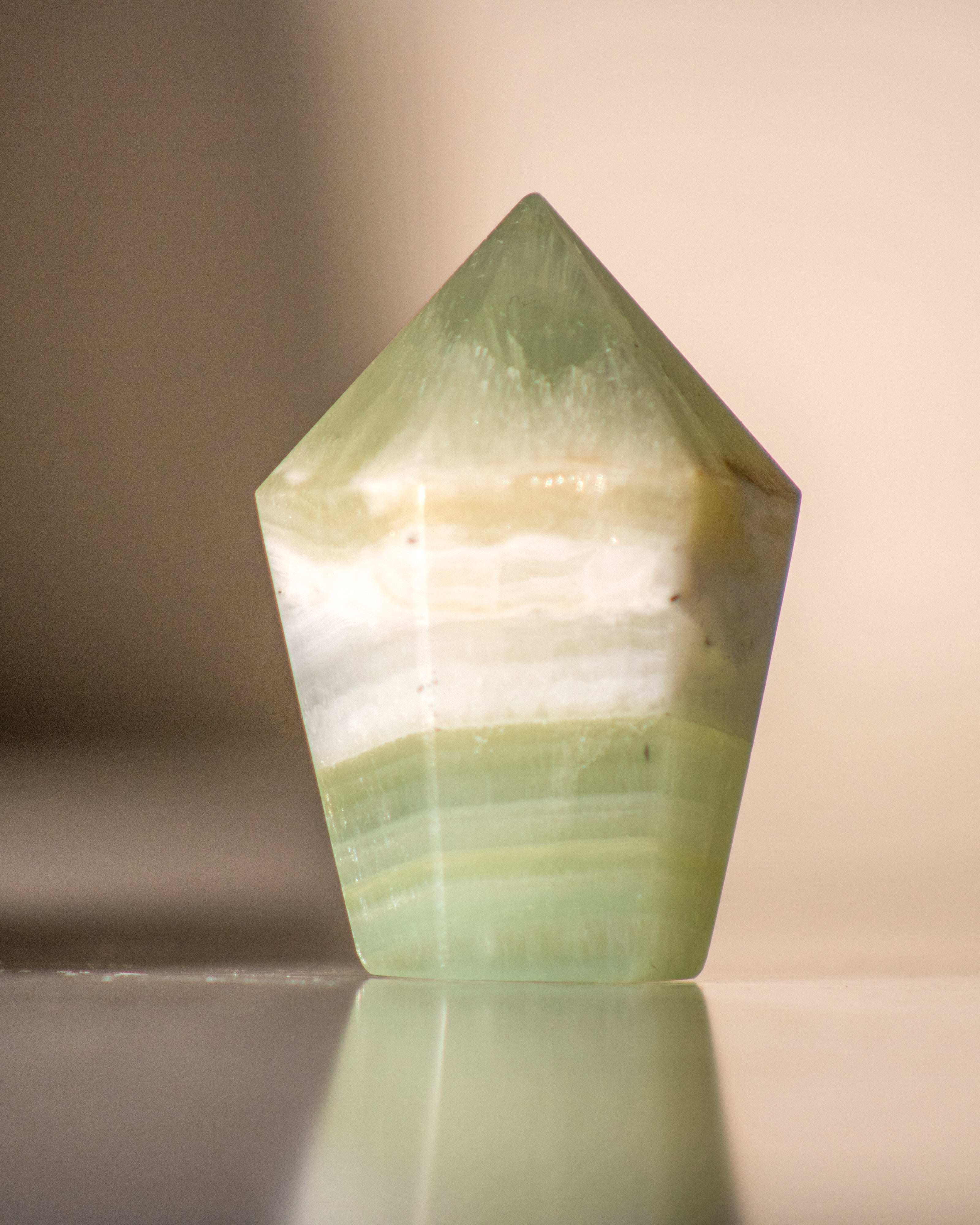 Green crystal tower on a reflective surface with a neutral background