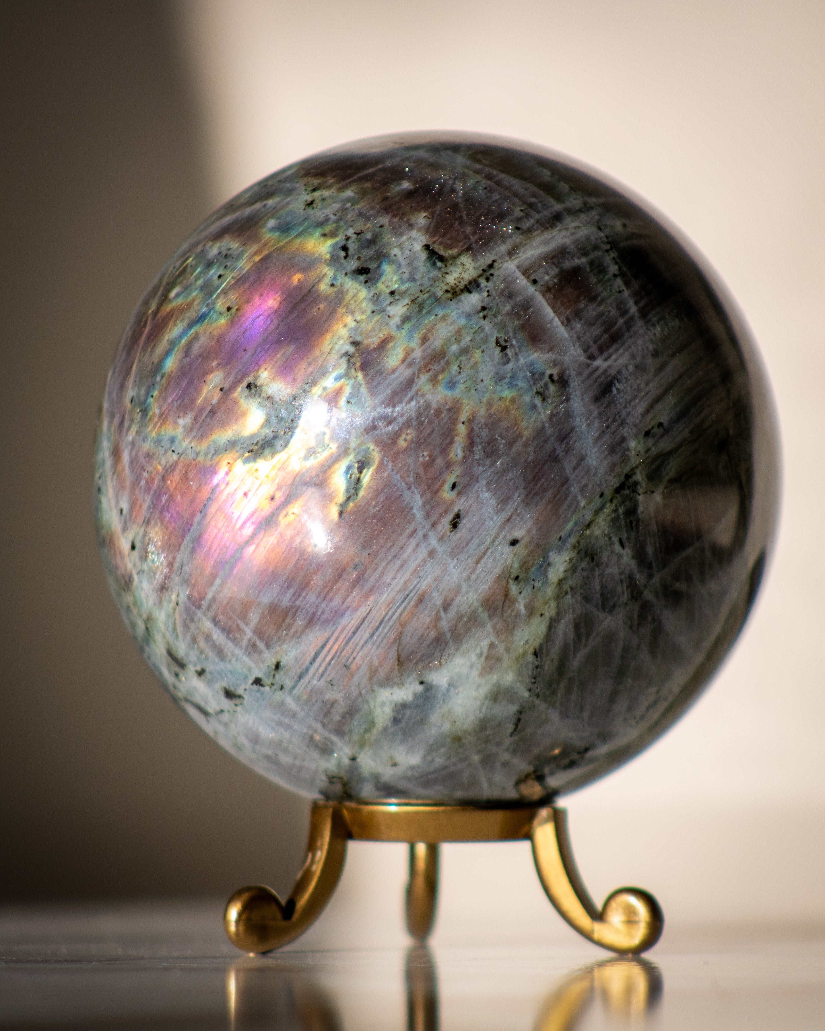 Labradorite crystal sphere on a stand with a neutral background