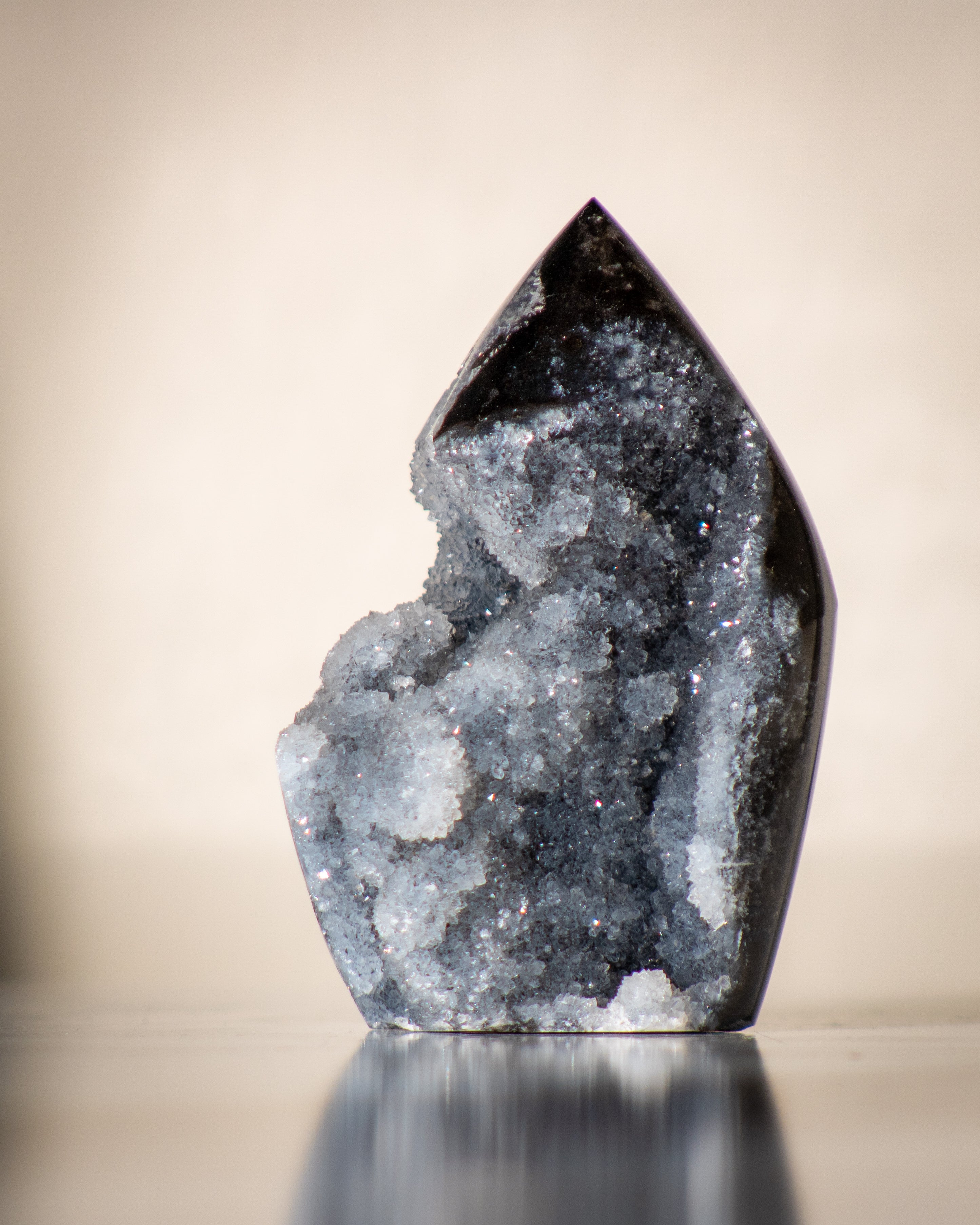 Geode crystal on a reflective surface with a neutral background