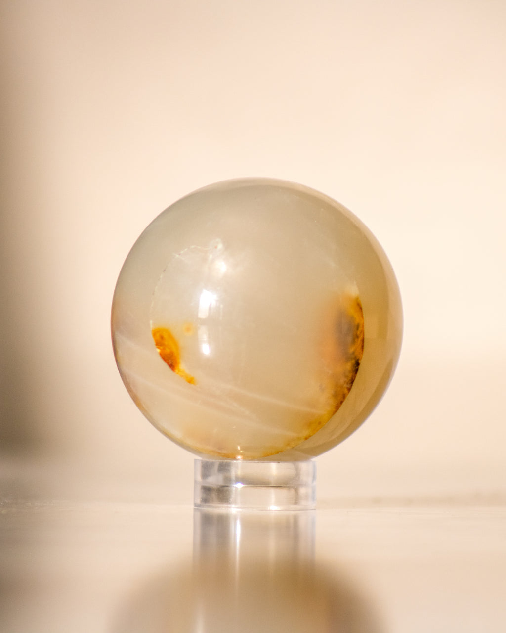 a beige moonstone ball on a small plastic stand