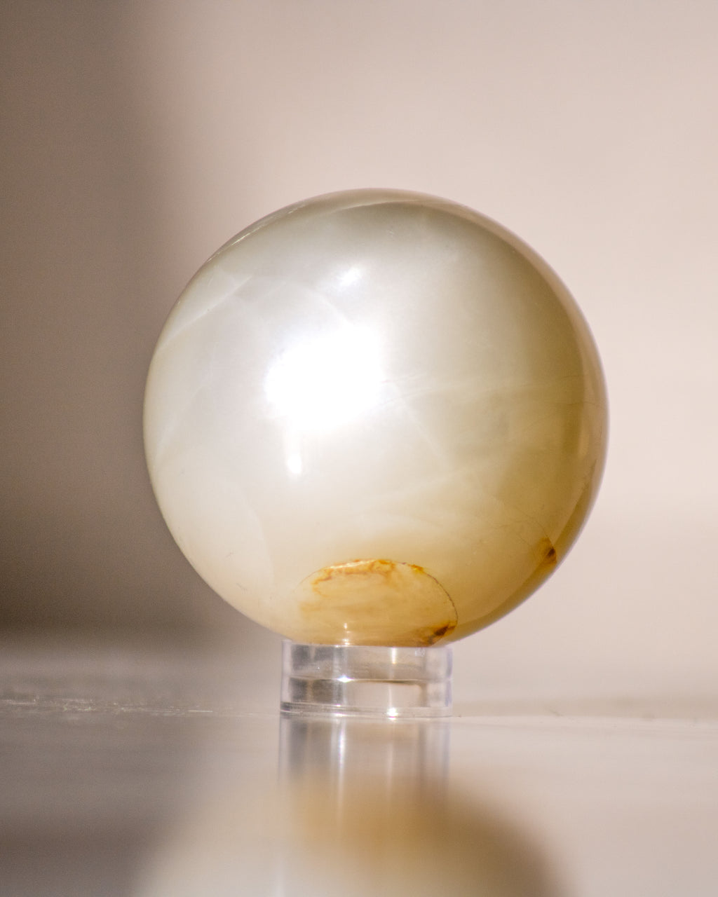 a beige moonstone ball on a small plastic stand