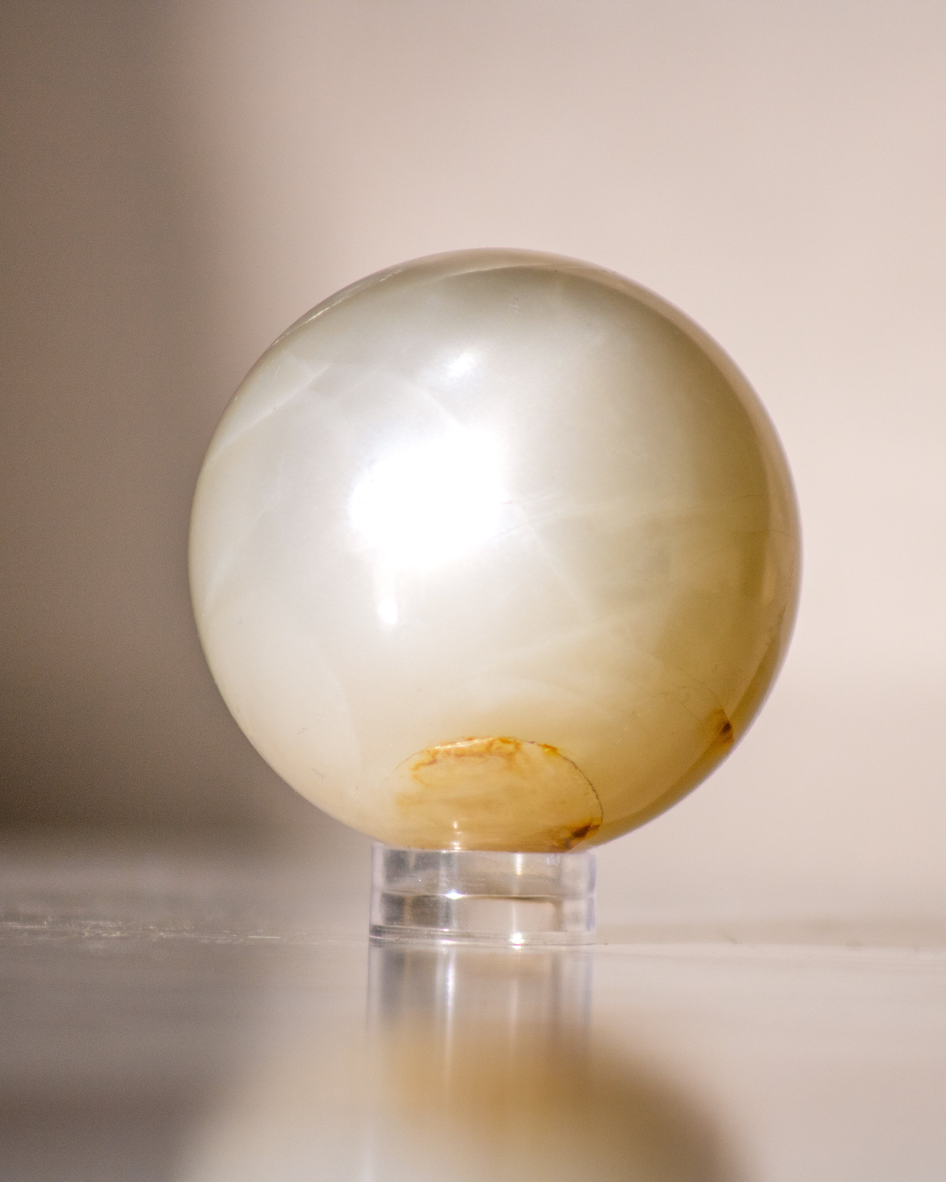 a beige moonstone ball on a small plastic stand