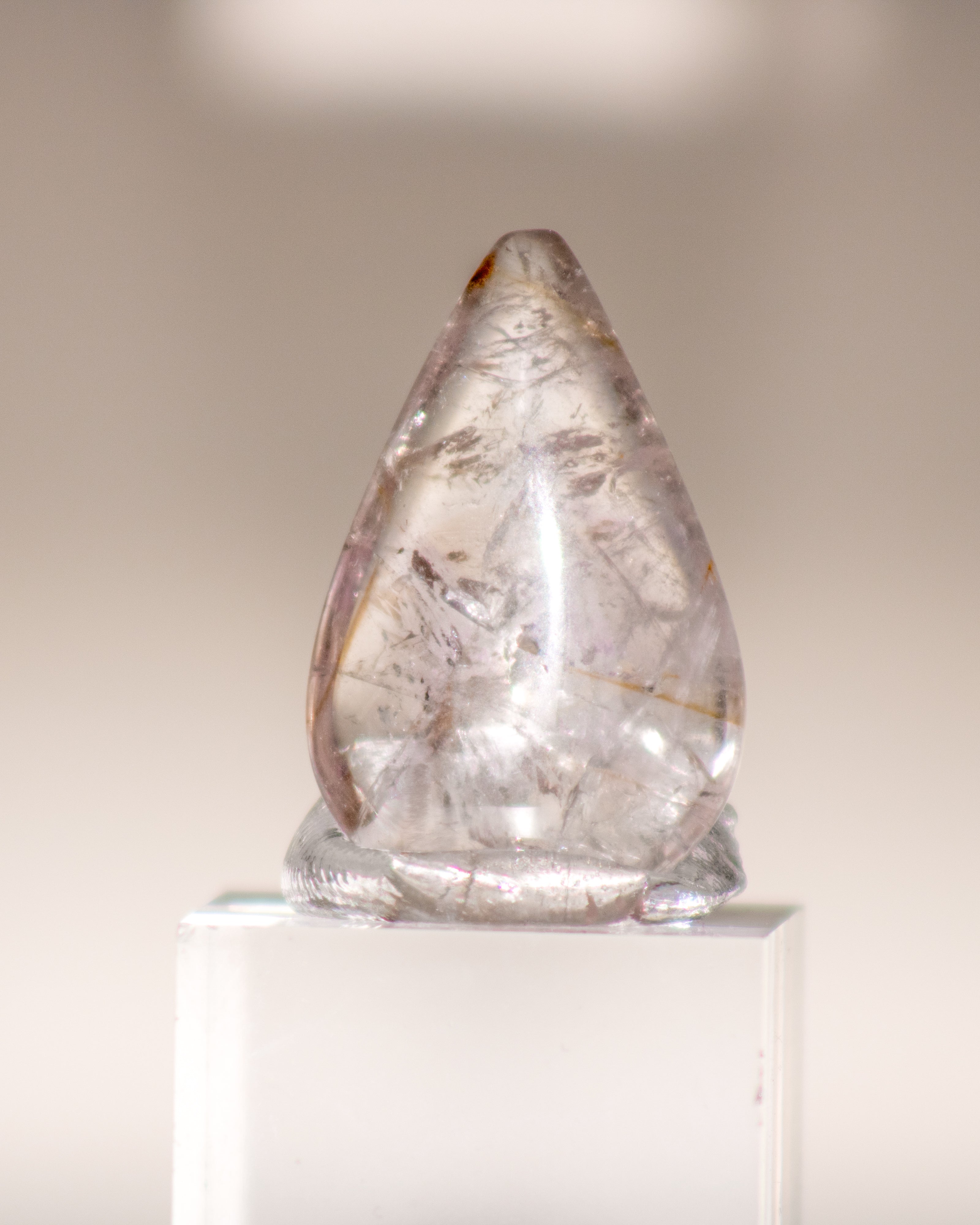 a clear quartz crystal teardrop with brown lines running through it