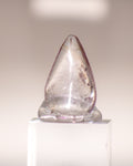 a clear quartz crystal teardrop with pale brown lines running through it 