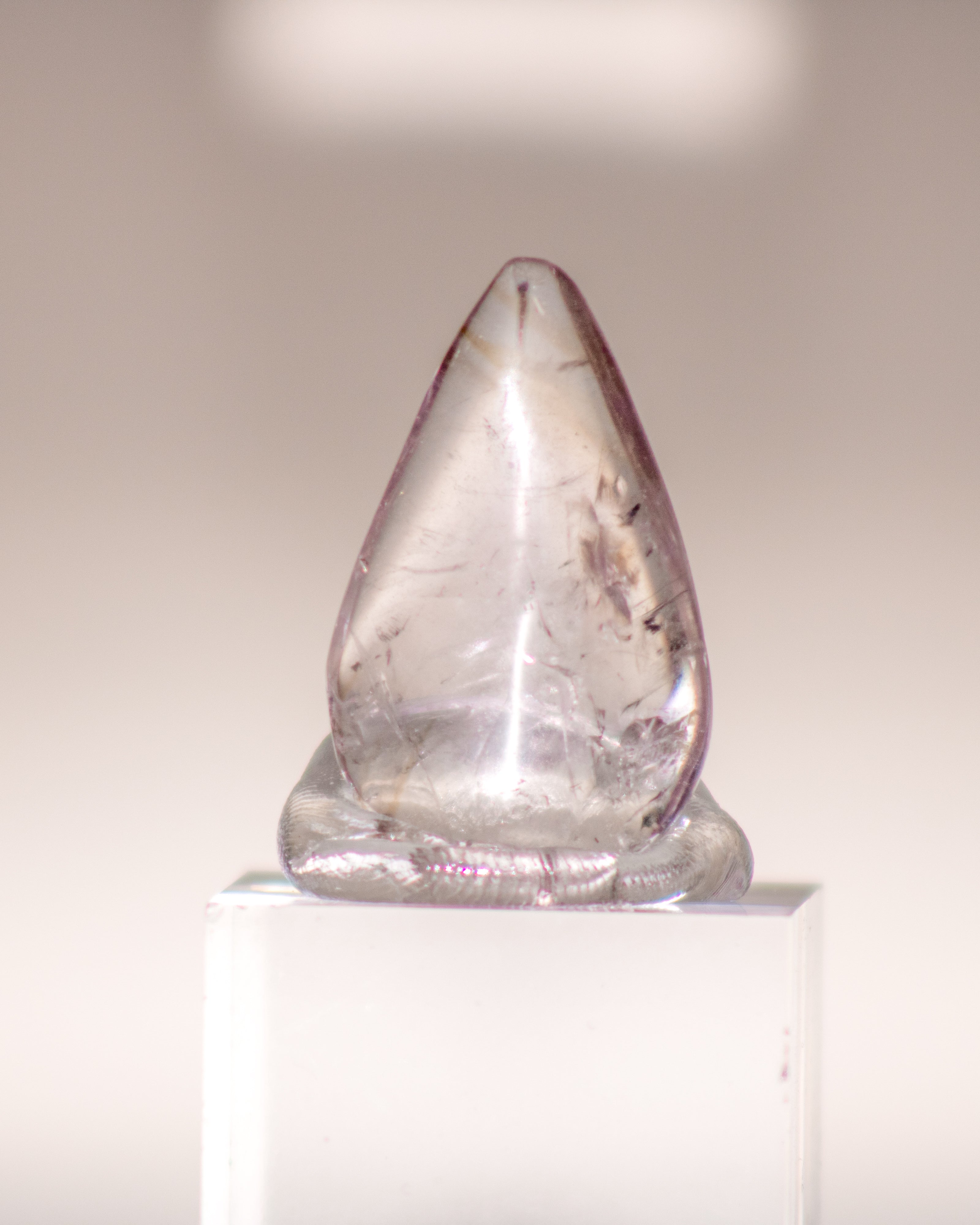 a clear quartz crystal teardrop with pale brown lines running through it 