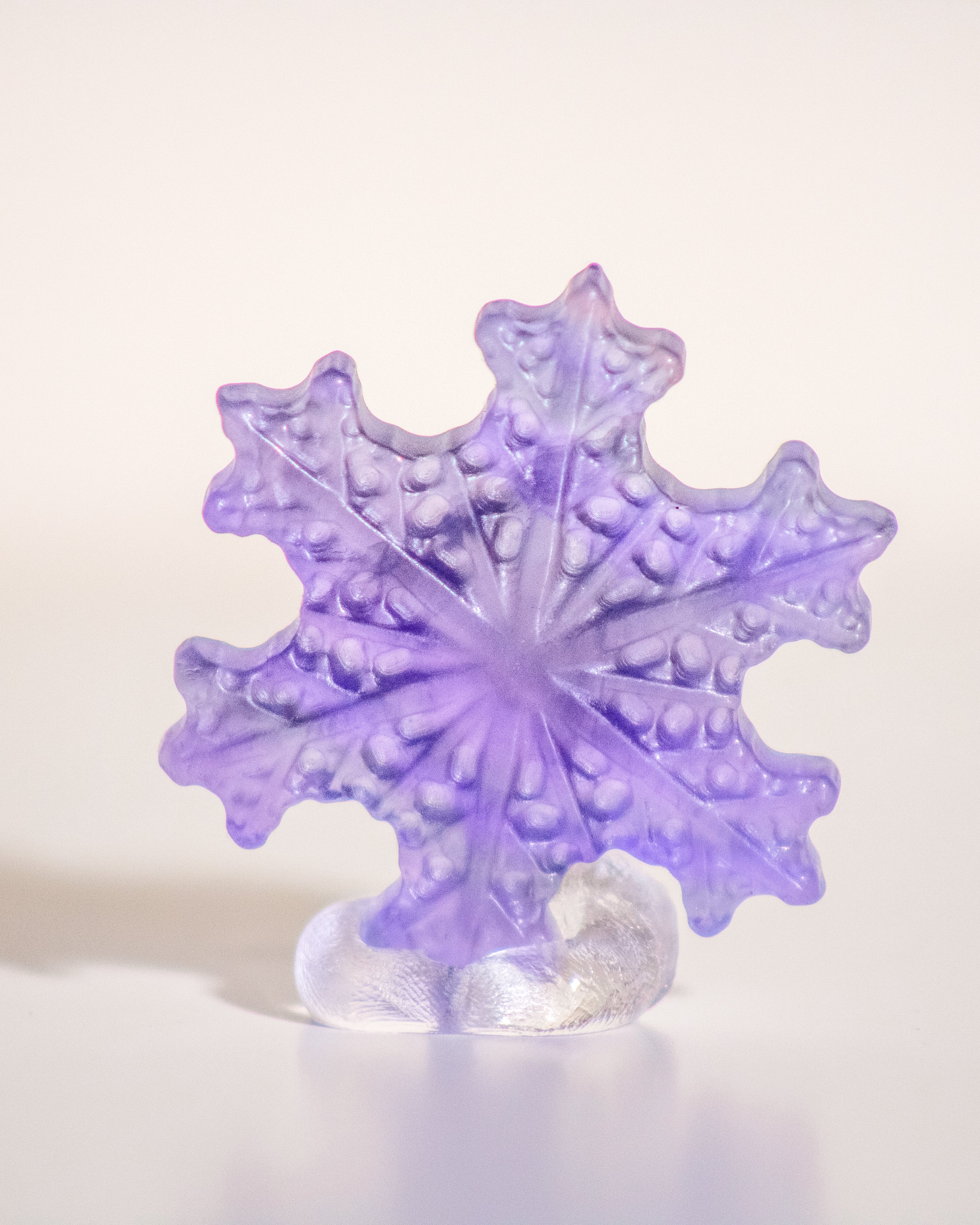 a carved purple fluorite crystal in the shape of a snowflake