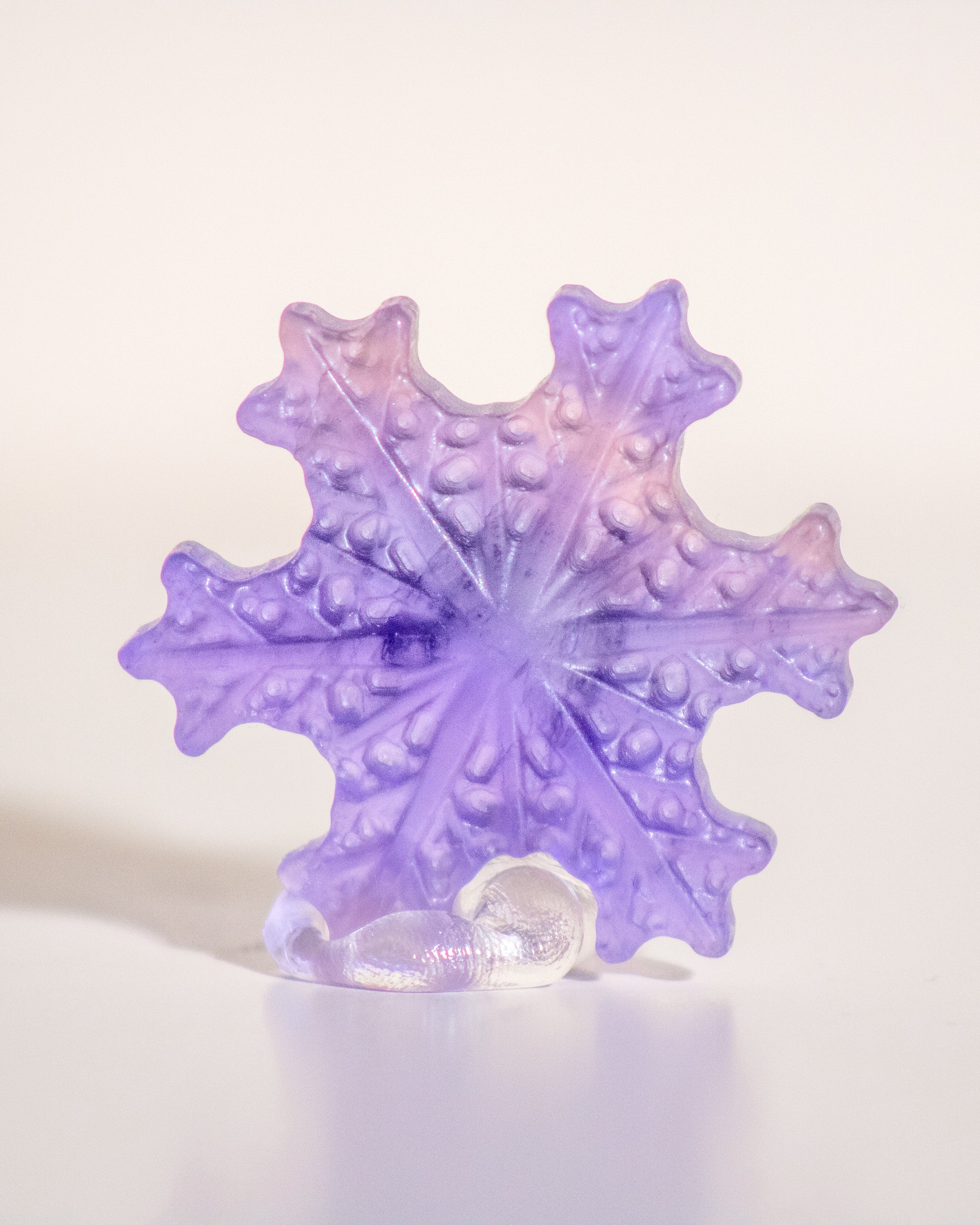 a carved purple fluorite crystal in the shape of a snowflake