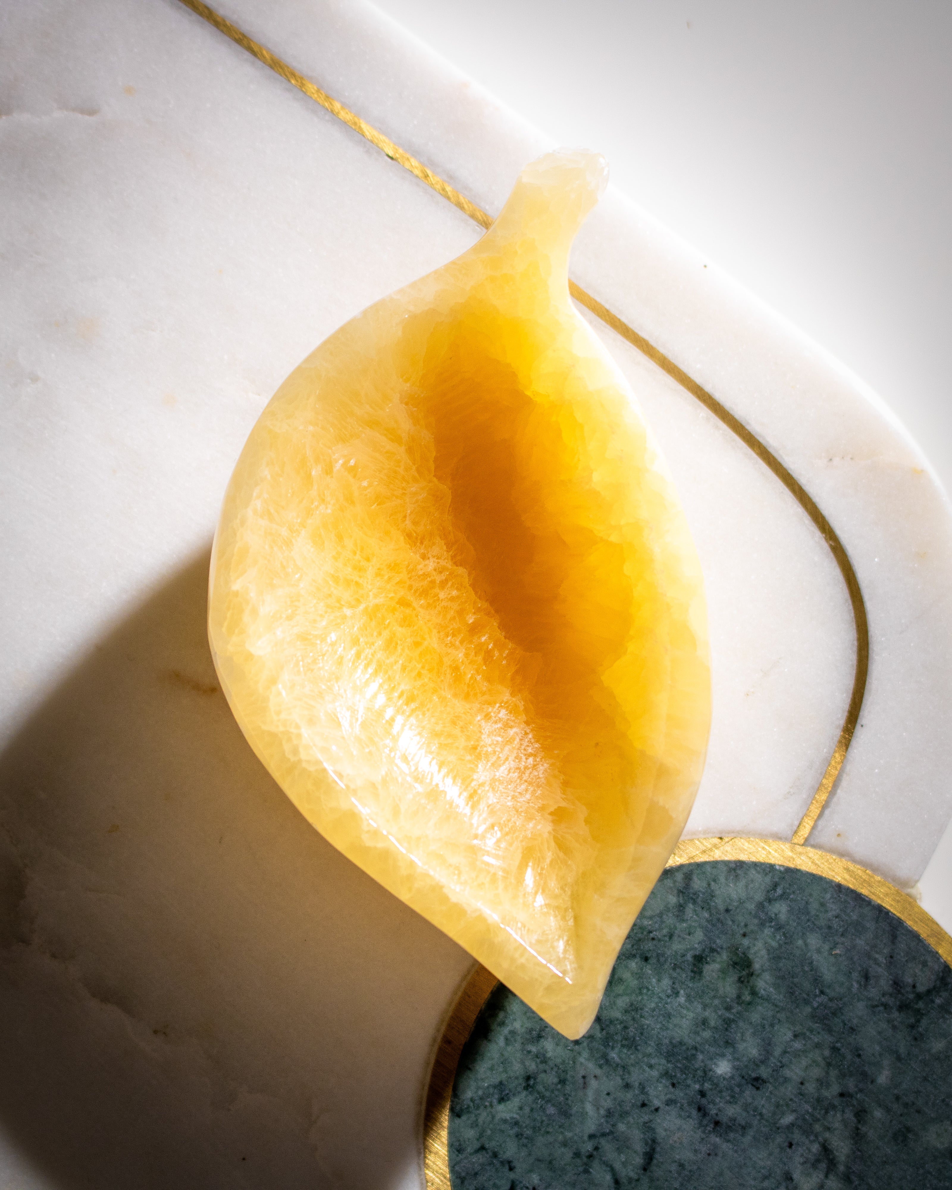 a bright orange calcite crystal carved into a leaf shaped bowl on a white background