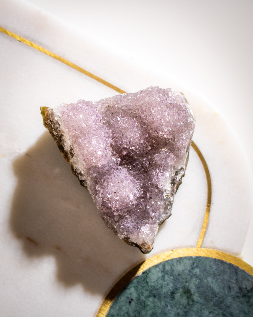 Amethyst crystal on a white surface with gold and green accents