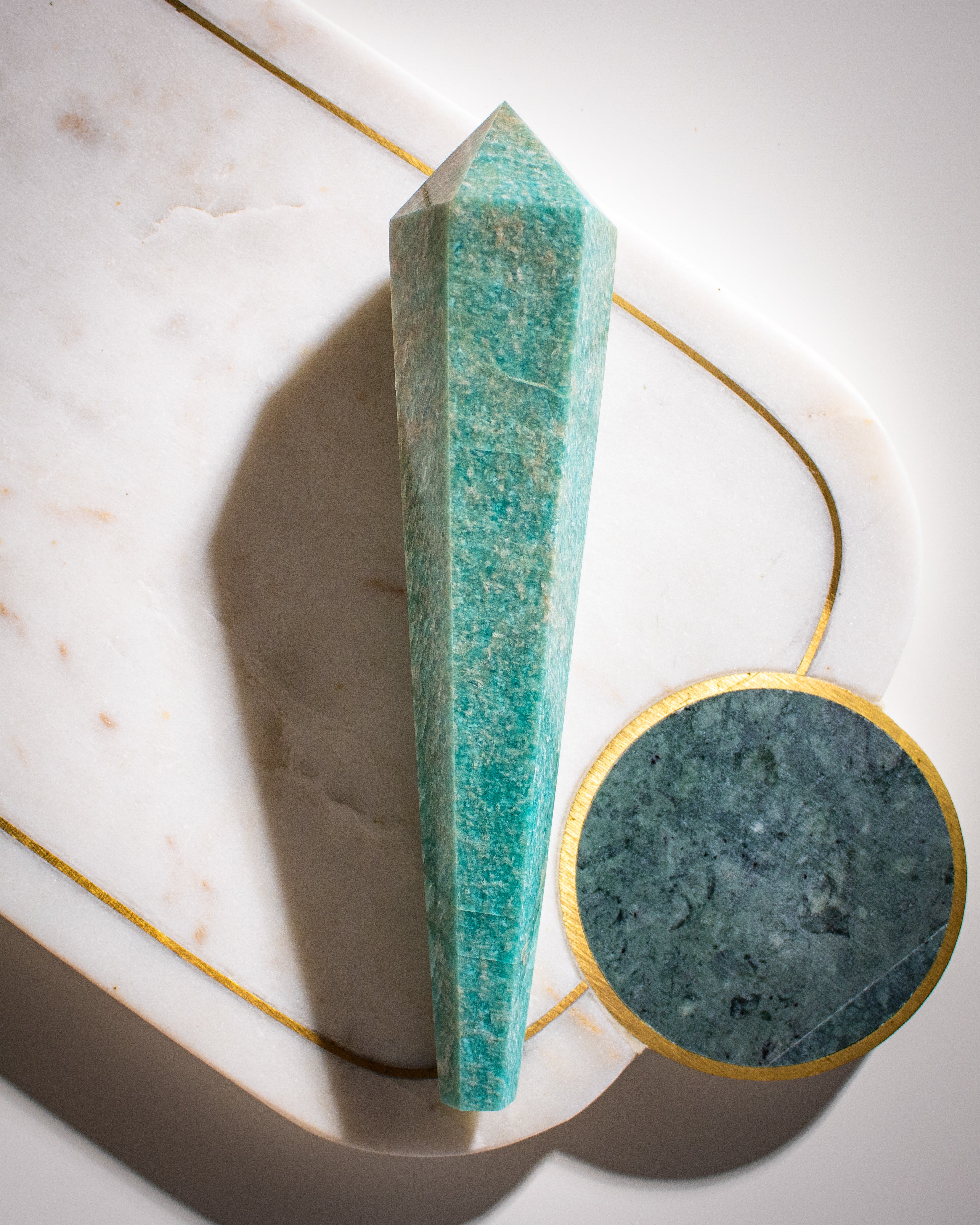 A large green amazonite crystal shaped like a long wand, tapered and pointed at both ends on a white background.