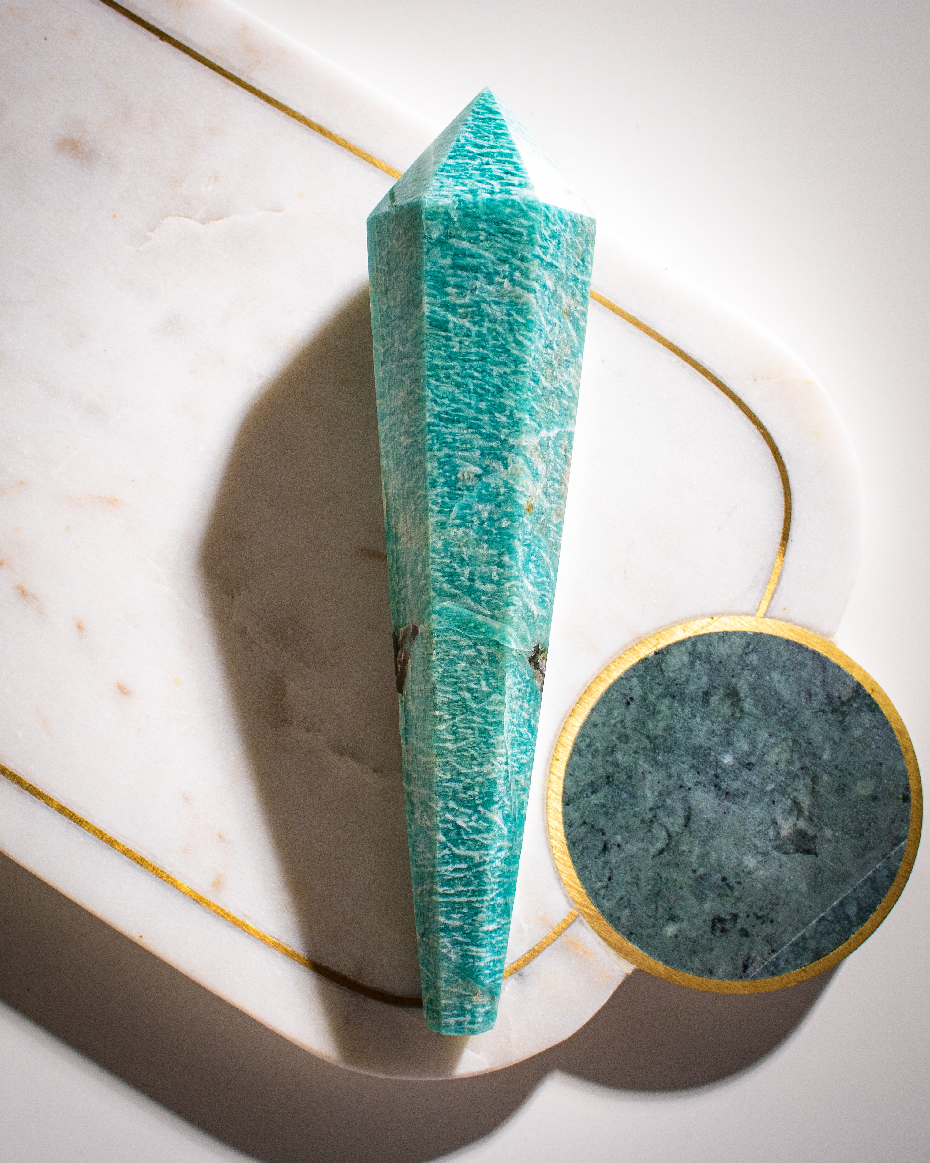 A large long green Amazonite crystal shaped into a tapered wand with points at both ends on a white background.