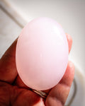 Pink stone held in a hand with a blurred background