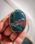 Oval-shaped stone held in a hand with a blurred background