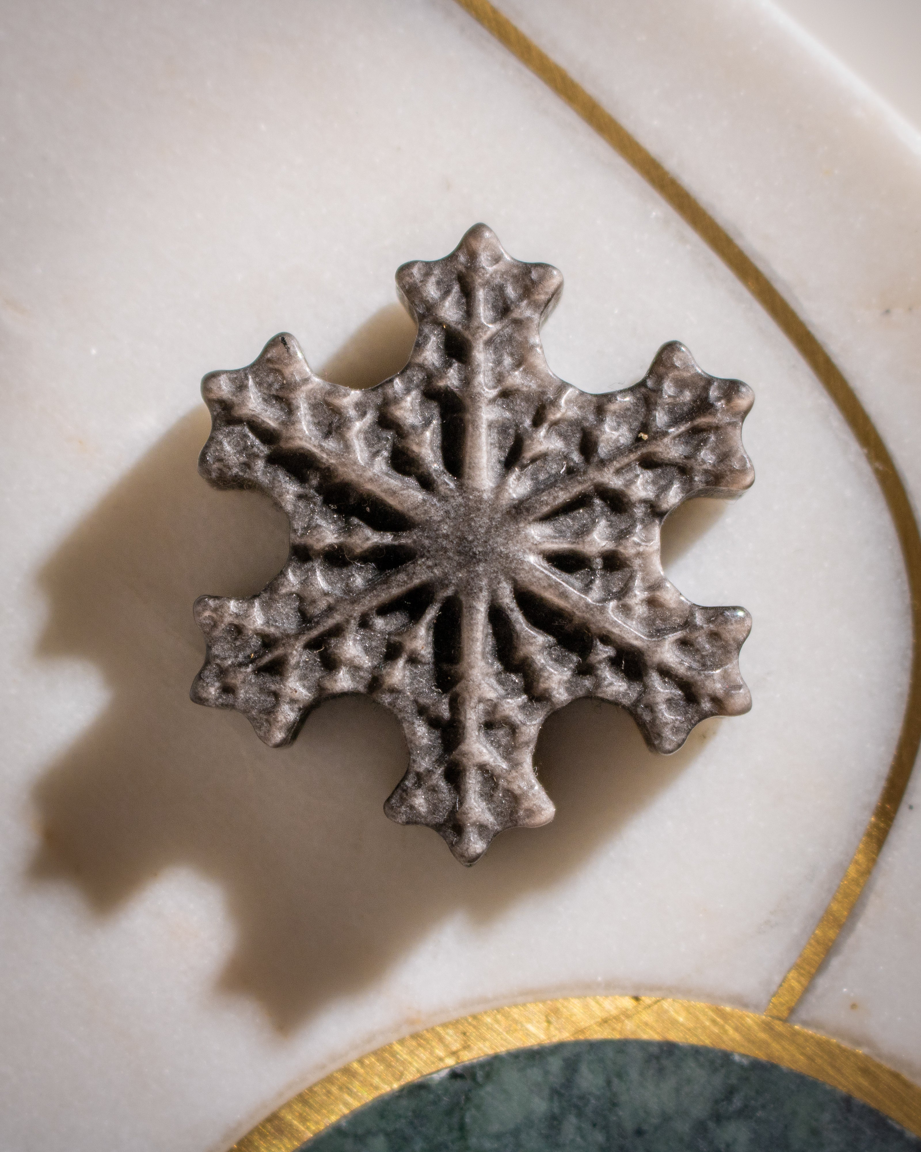 Decorative snowflake on a marble surface with gold accents
