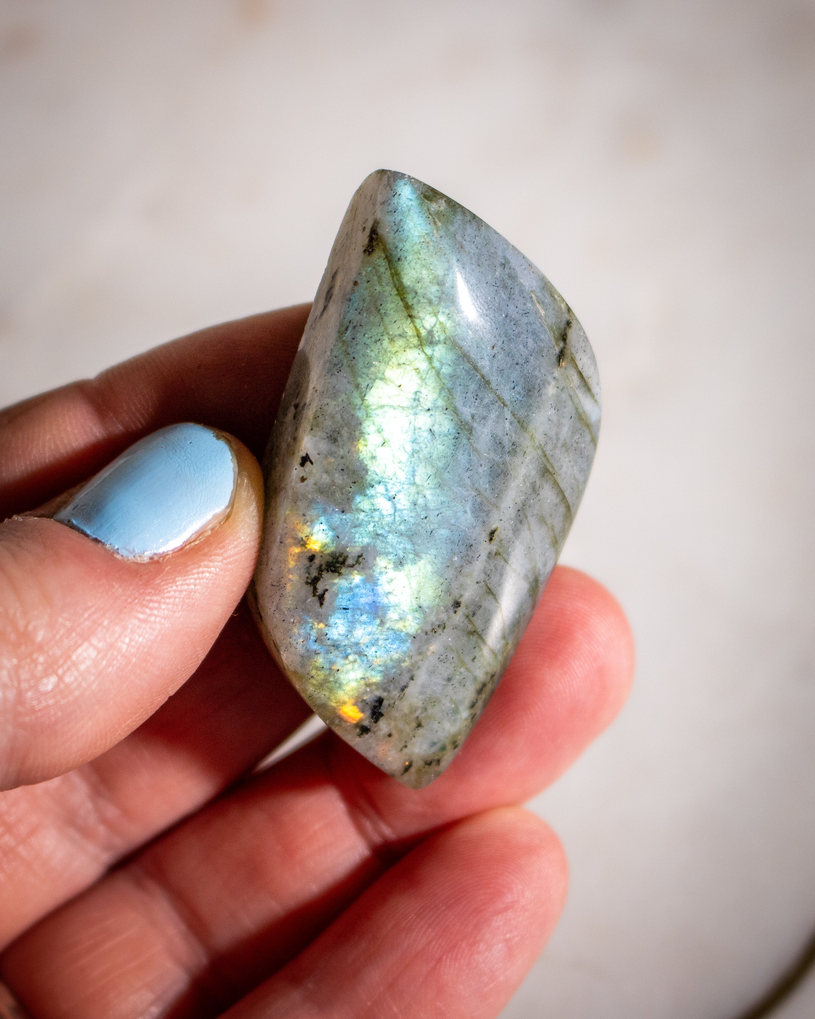 Hand holding a labradorite stone with a blurred background
