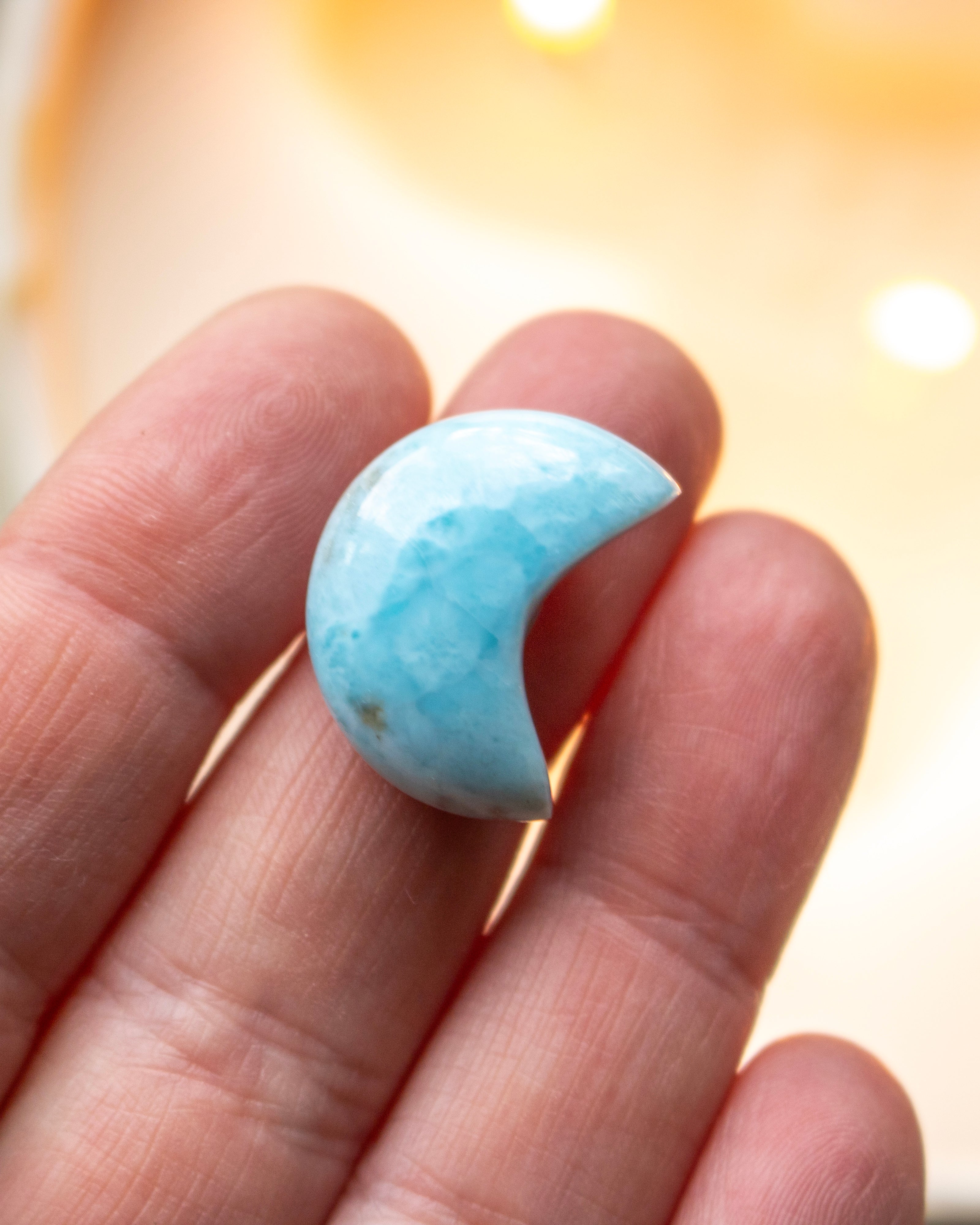 a small blue crescent shape stone resting on fingers of a hand