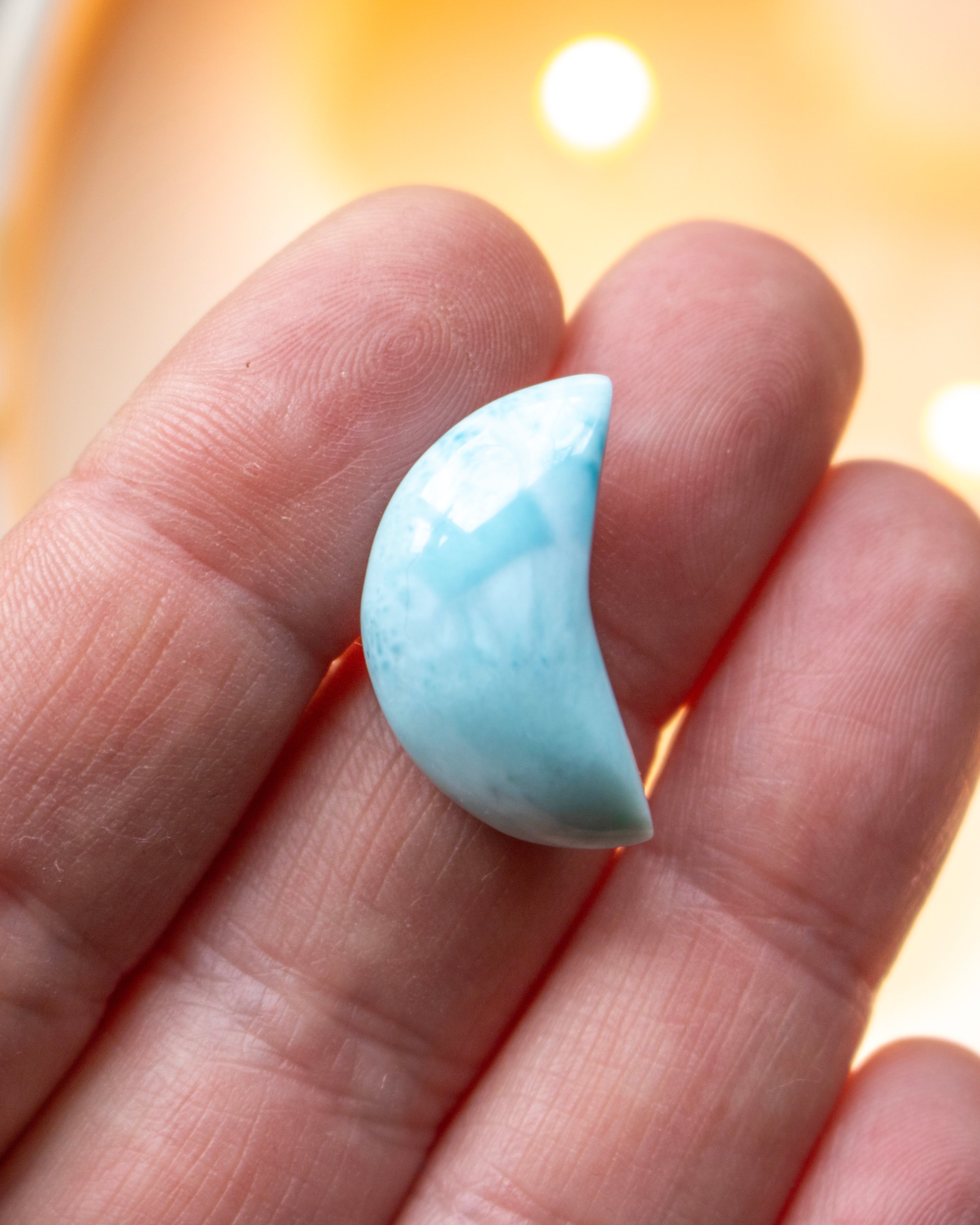 a small blue crescent shape stone resting on fingers of a hand