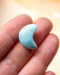 a small blue crescent shape stone resting on fingers of a hand