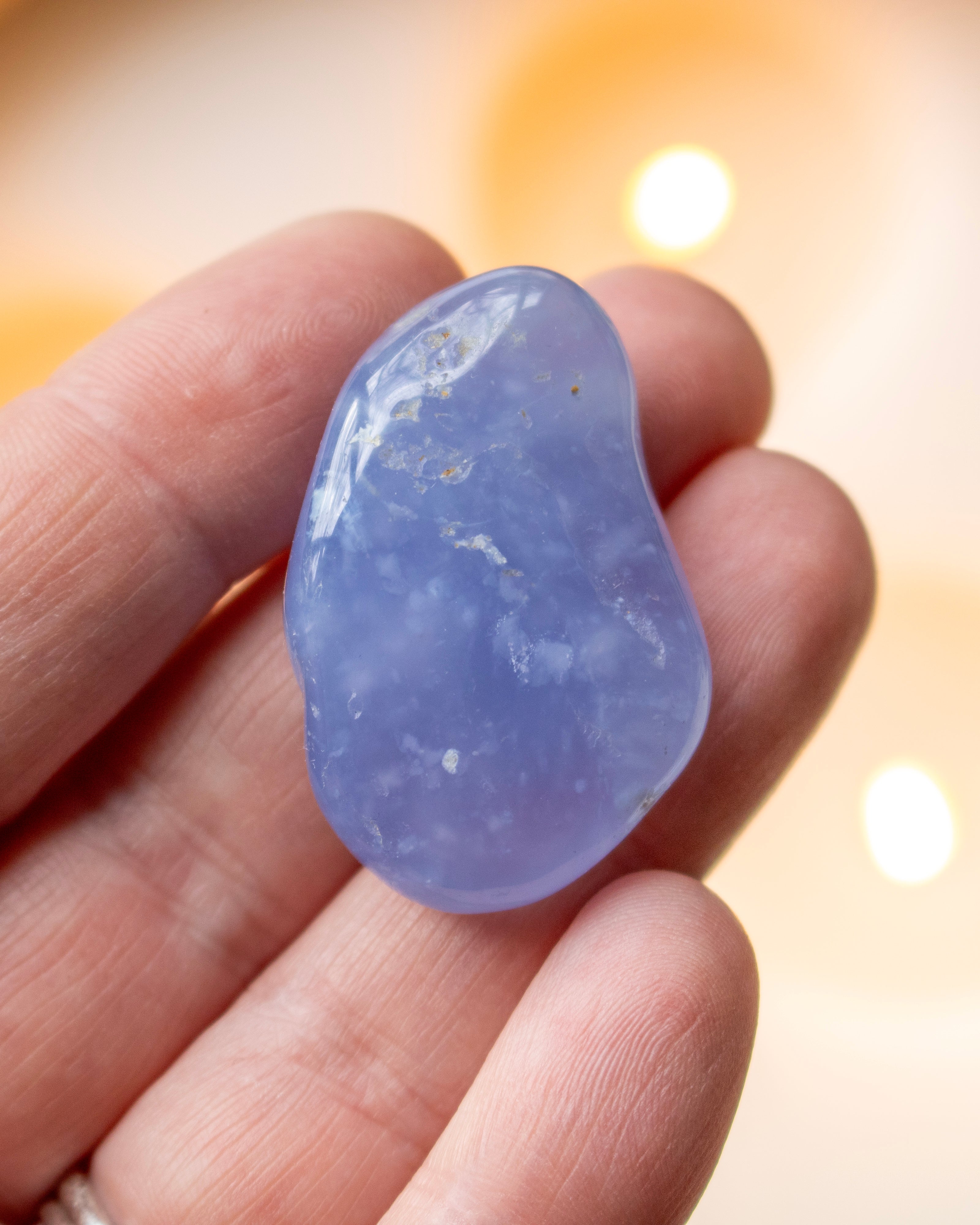 Blue crystal held between fingers with a blurred background