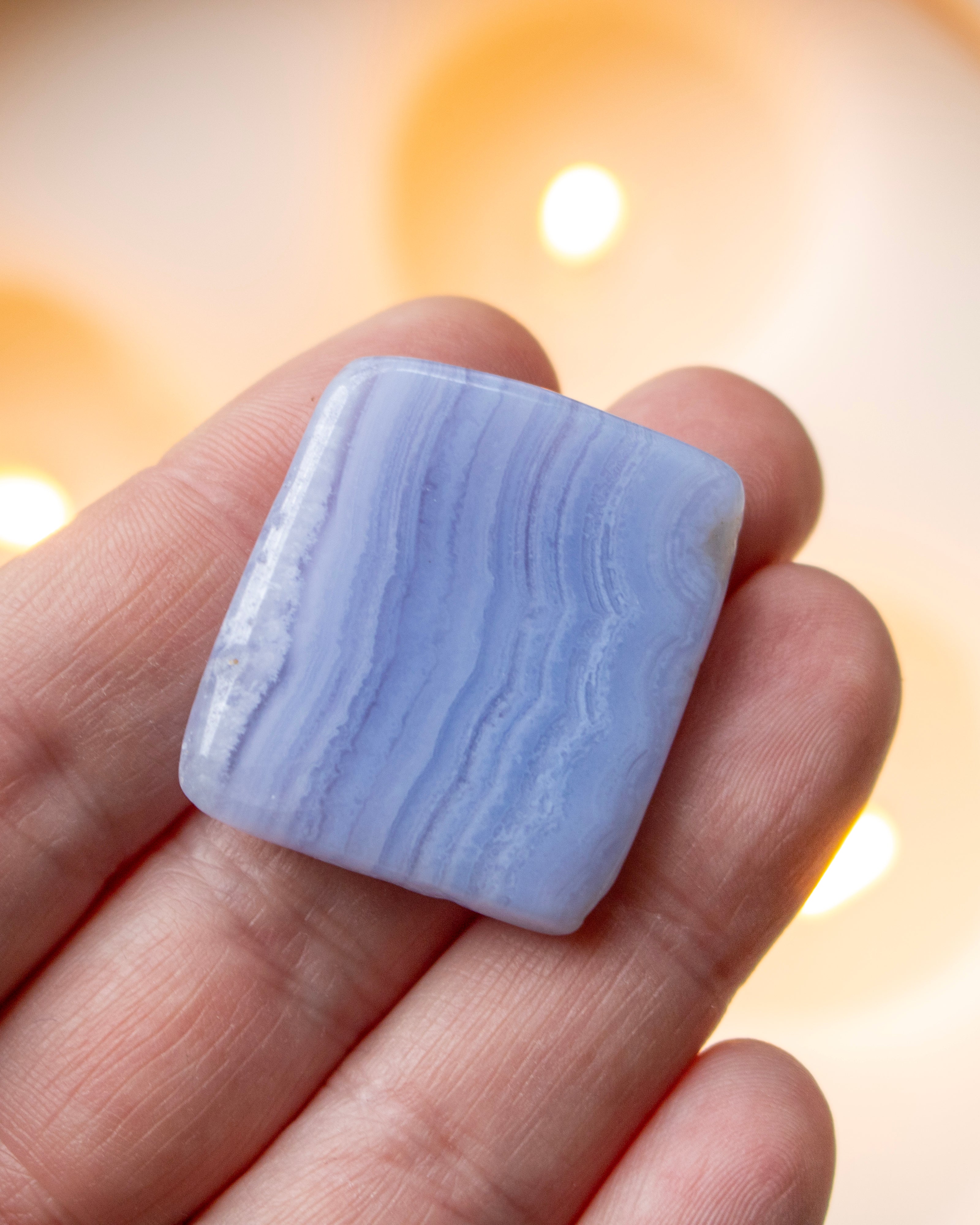 Blue lace agate stone held in a hand with a warm light background