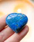 Heart-shaped blue stone held in a hand with a blurred background