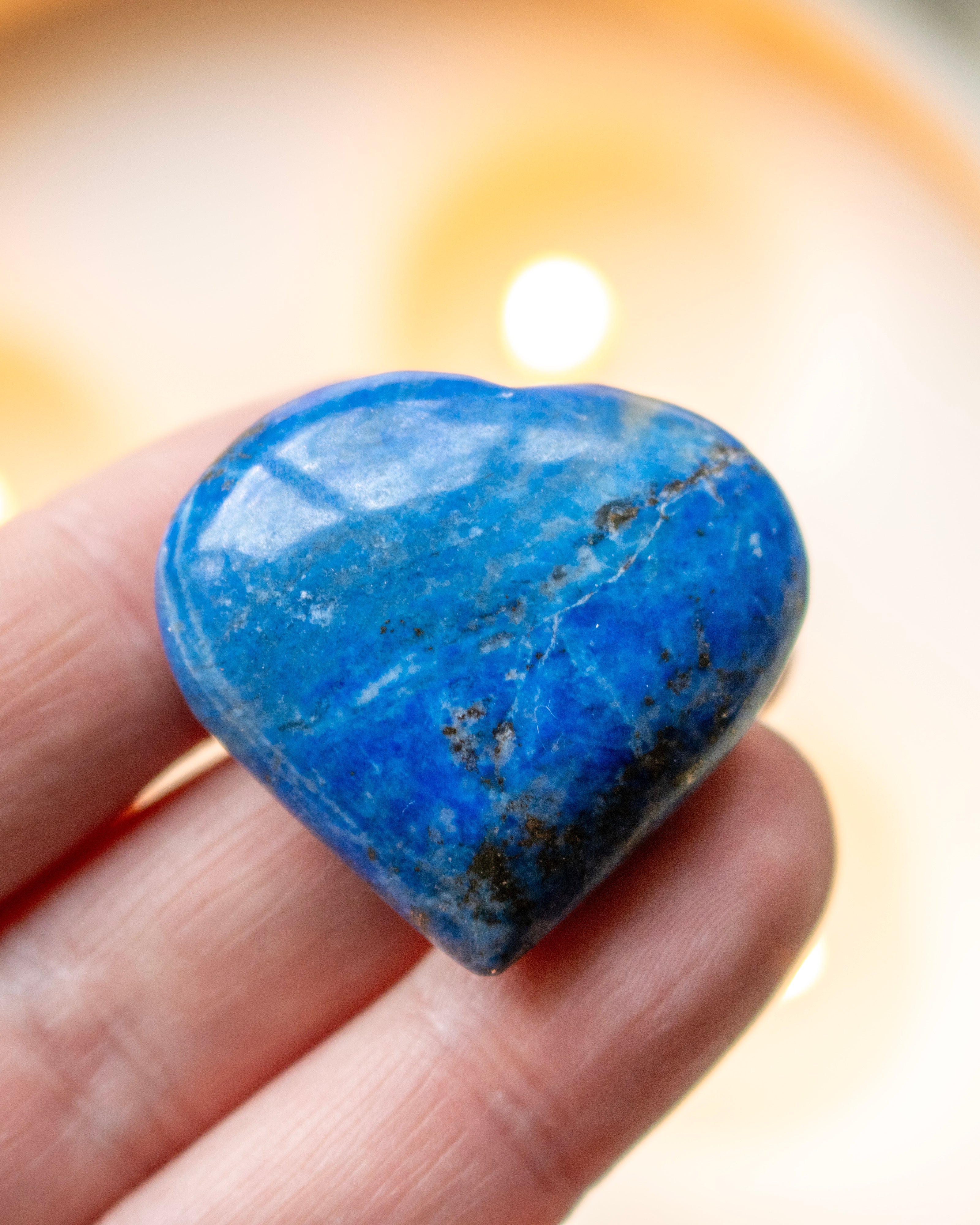 Heart-shaped blue stone held in a hand with a blurred background