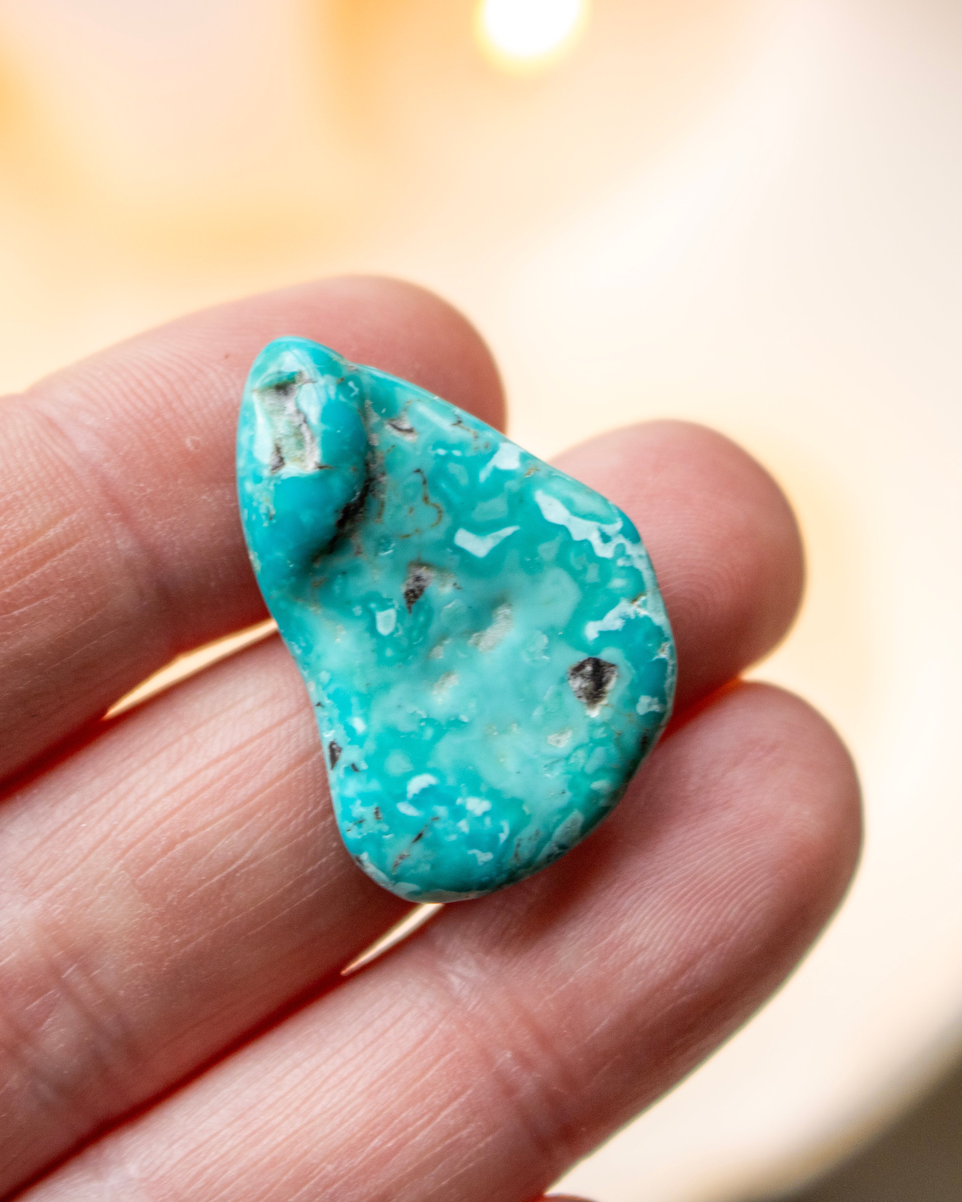 Turquoise stone held in a hand with a blurred background