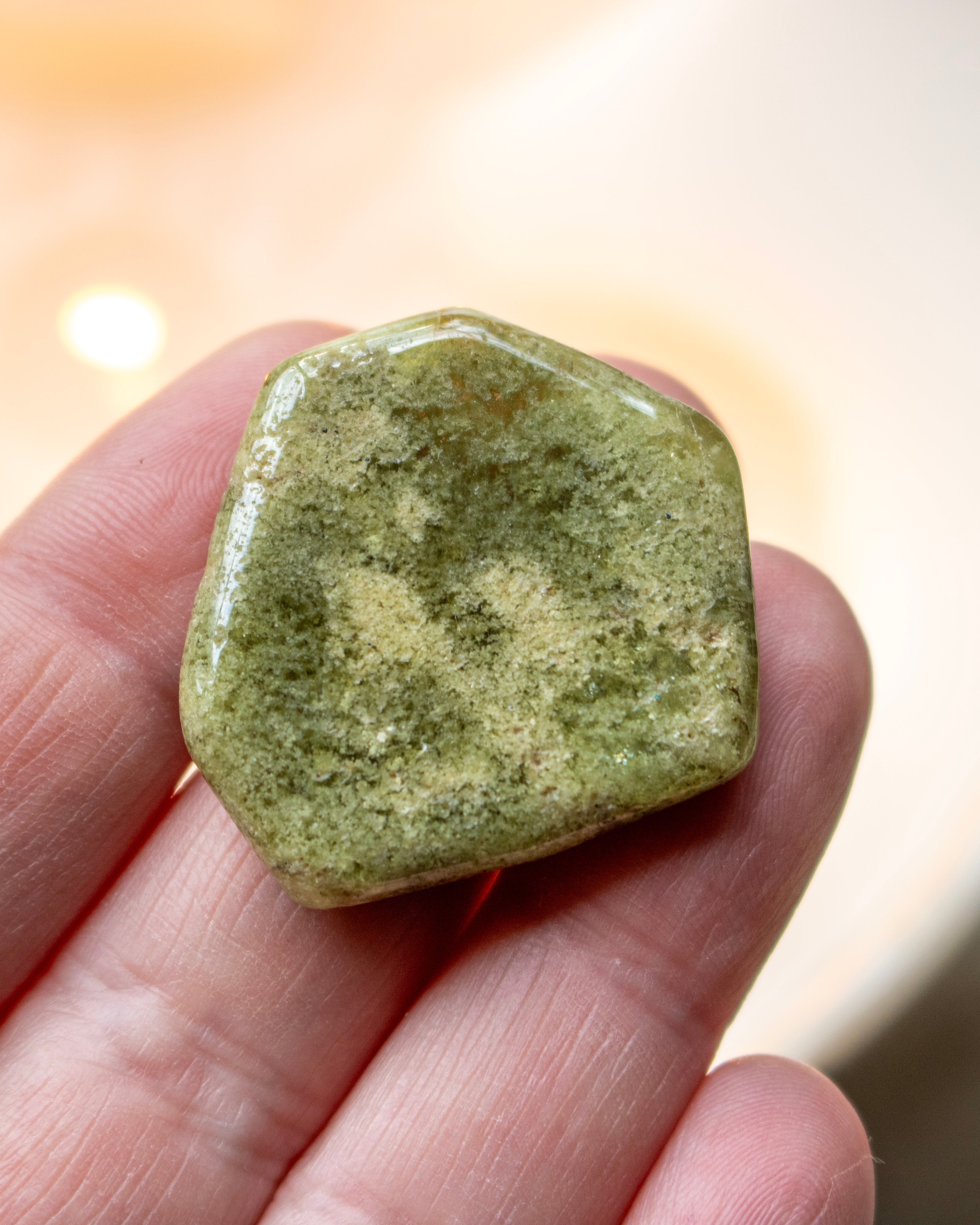 Green stone held in a hand with a blurred background