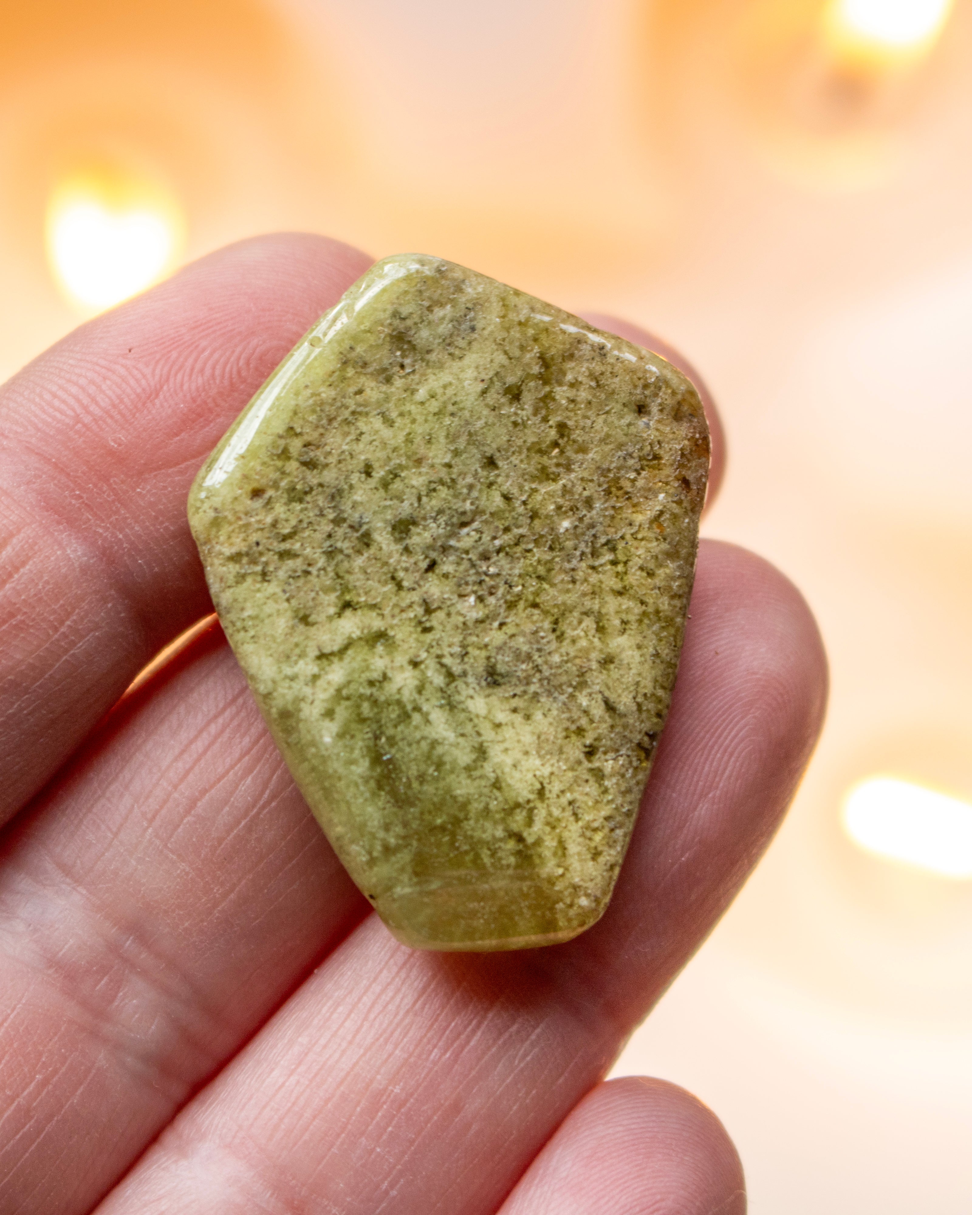 Green stone held in a hand with a blurred background