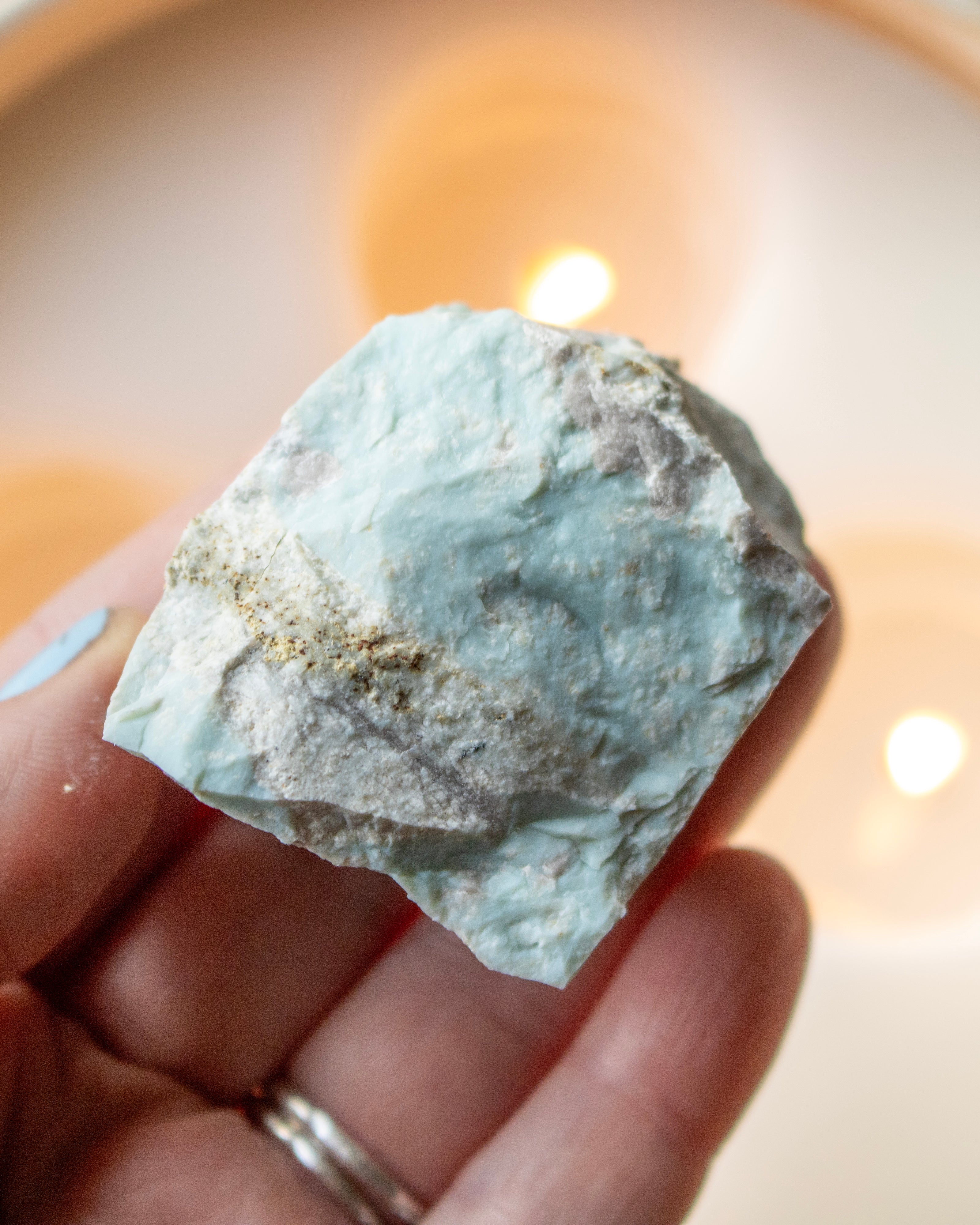 a hand holding a rough blue mineral
